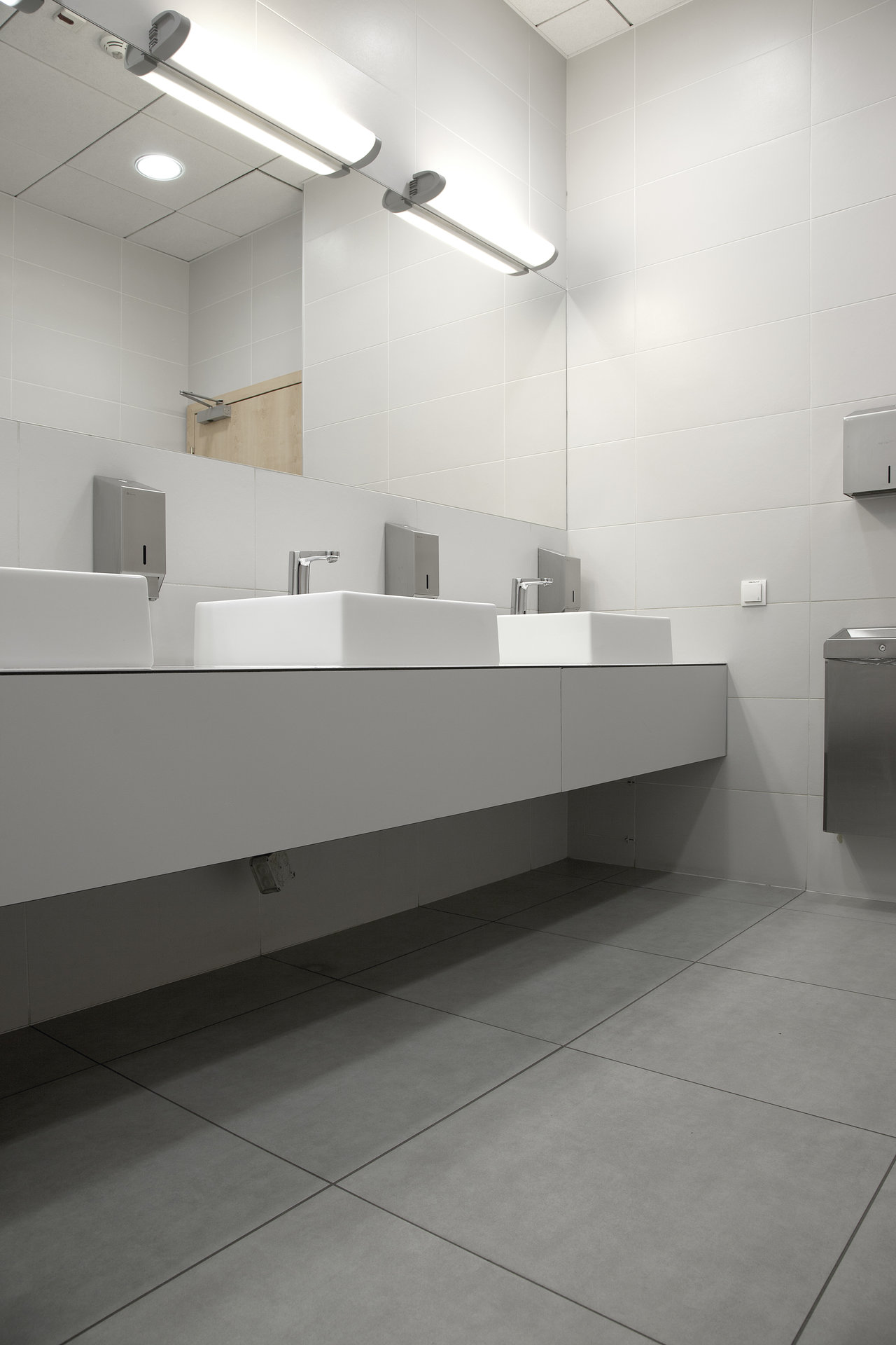 Bright washroom with modern, large-format grey porcelain tiles on floor and wall.