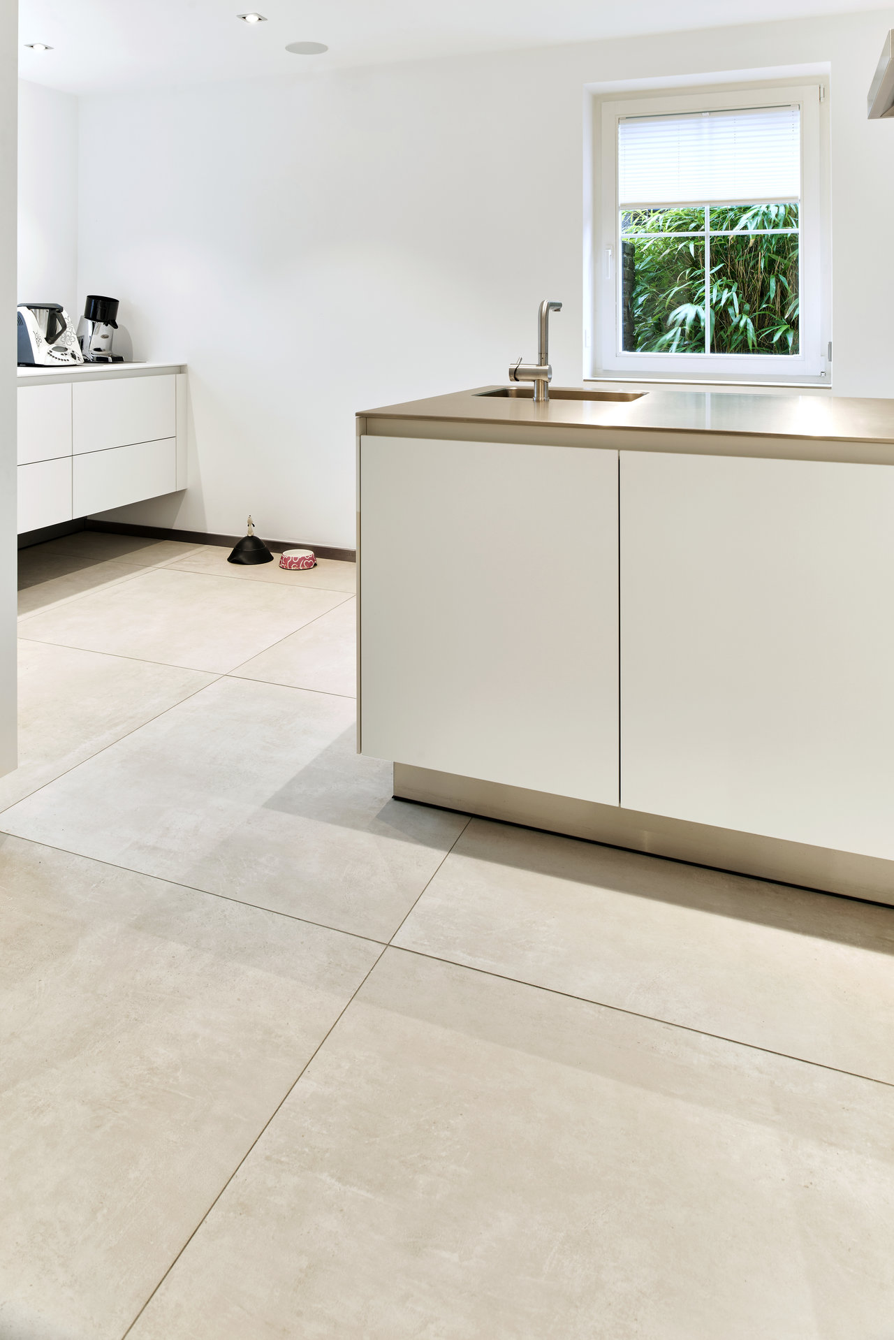 Modern, bright kitchen with large-format concrete-effect floor tiles.