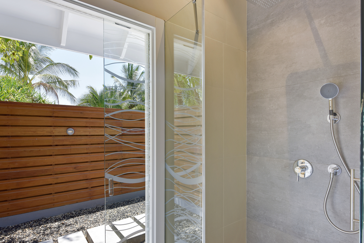 Exclusive outdoor shower with modern grey tiles and tropical flair.