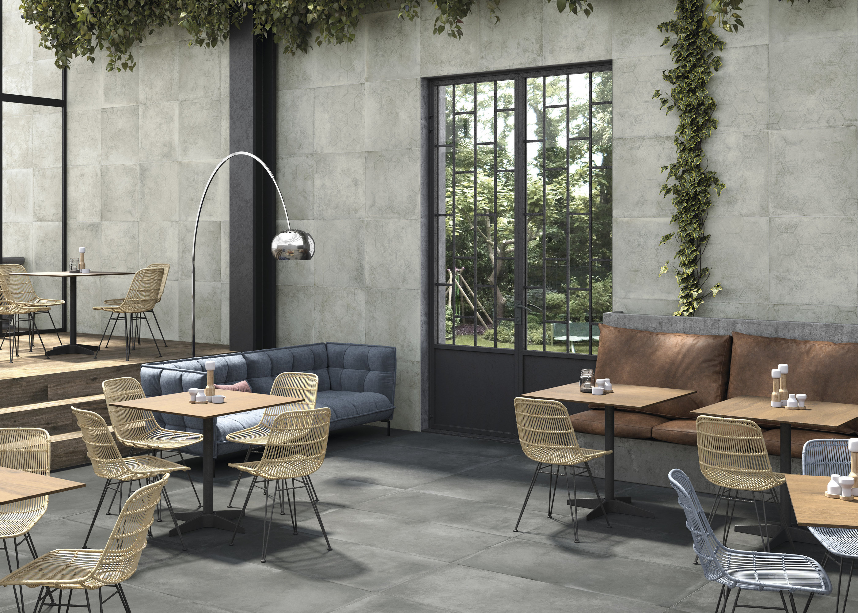 Spacious café with Porcelaingres concrete-look tiles on floor and walls and comfortable seating.