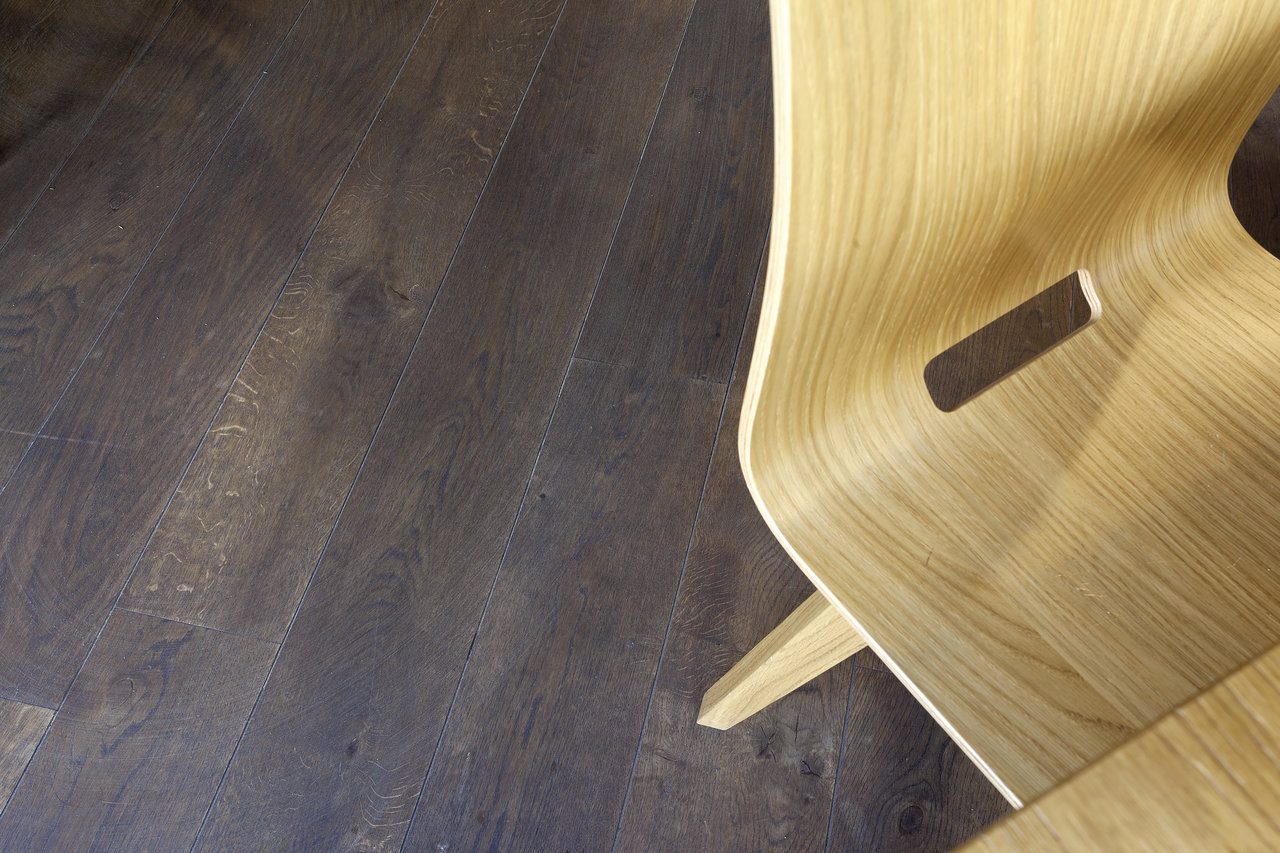 Dark wood-effect indoor tiles, beside a light wooden chair.