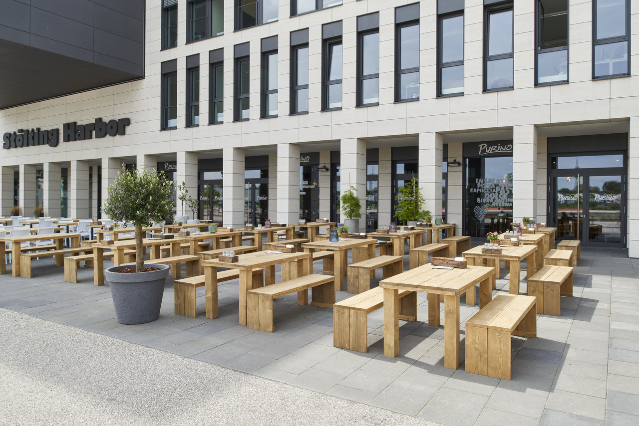 Modern outdoor terrace with wooden benches and tables on stylish outdoor tiles.