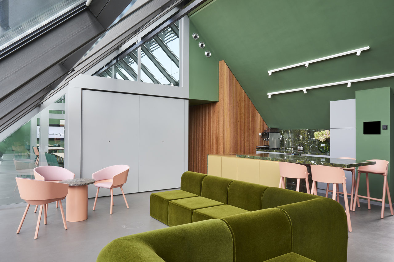 Modern loft interior with green velvet sofa and light tiled floor.