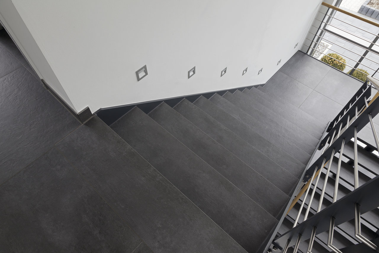 Modern staircase with high-quality, dark tiles and subtle wall lighting.