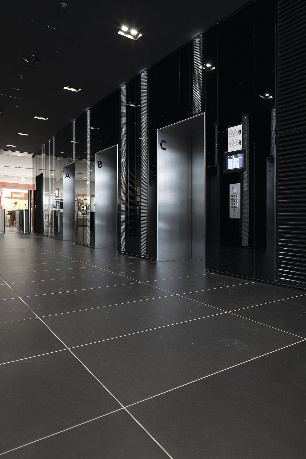 Large-format, dark grey tiles with light grout in a modern lobby.