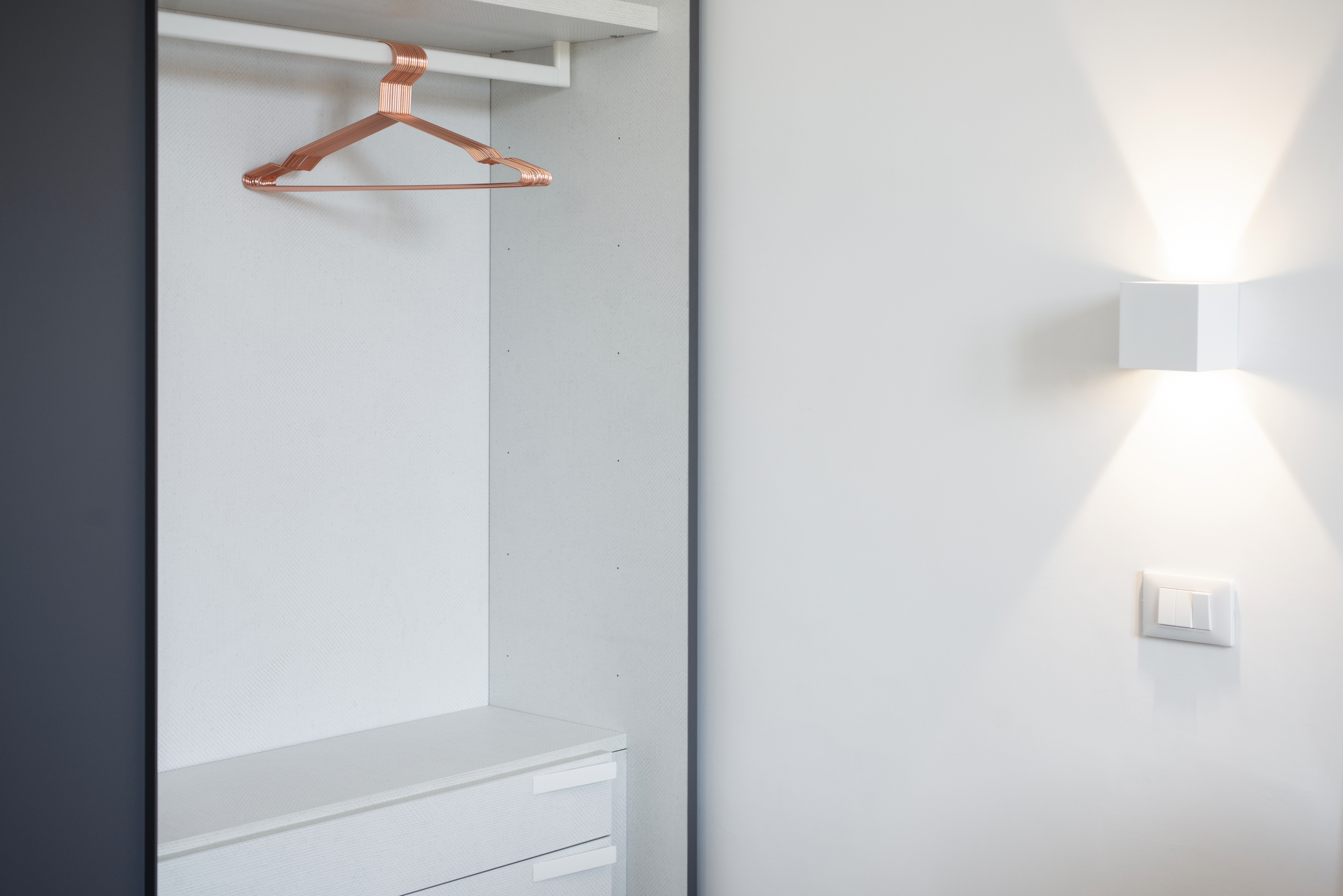 Modern, bright interior with white wardrobe and designer wall lamp.