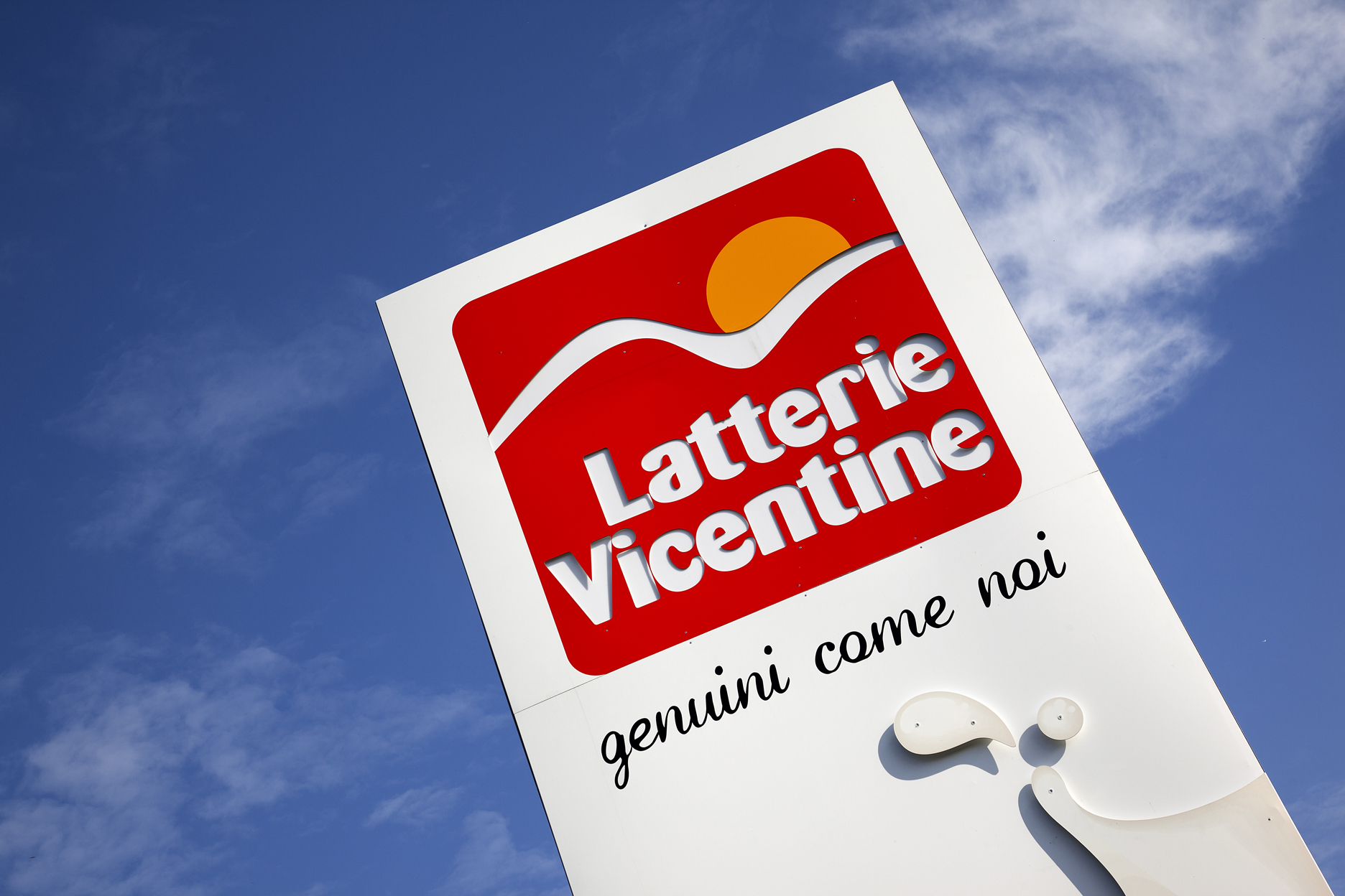 Latterie Vicentine dairy sign with logo and slogan against blue sky.