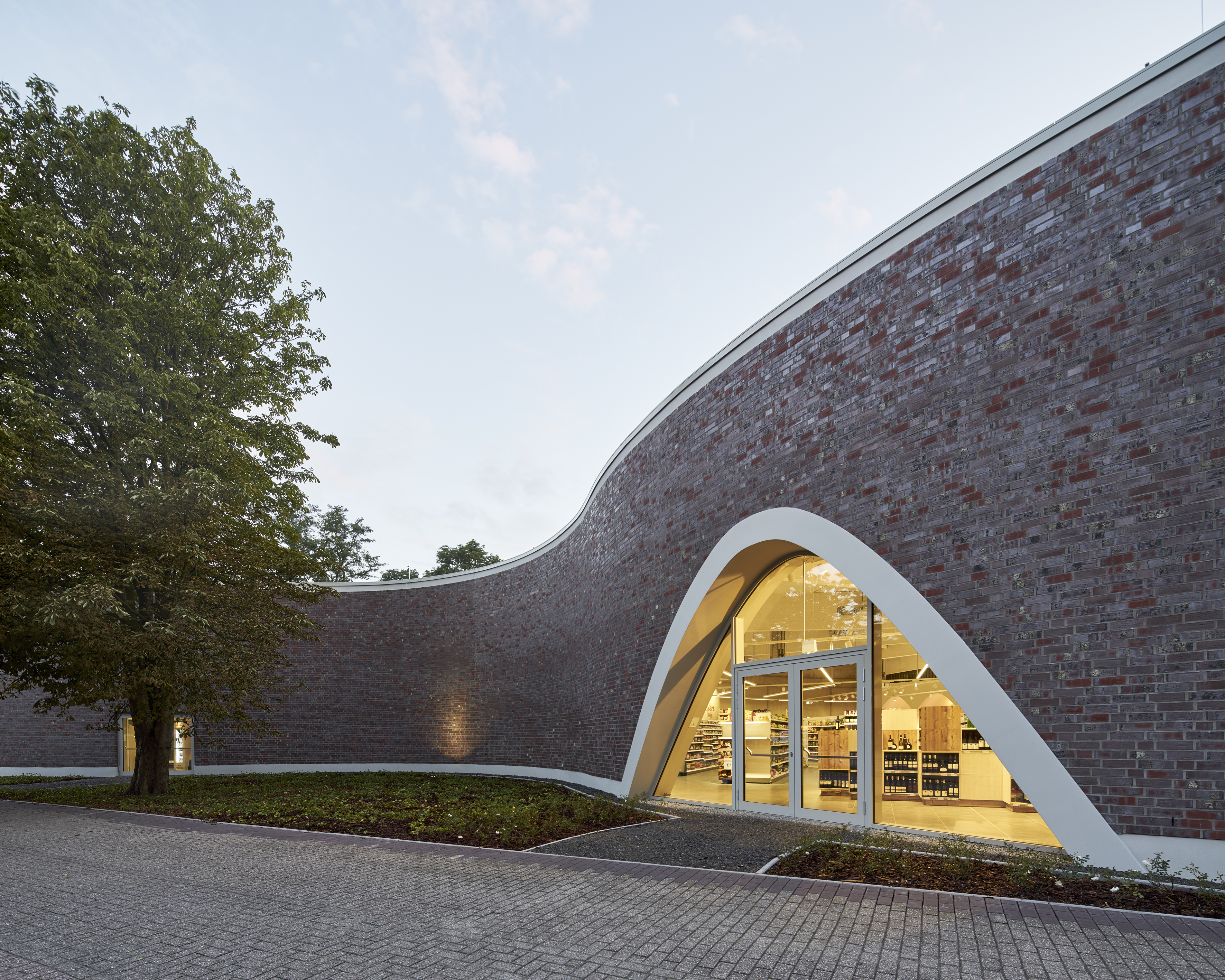 Modern architecture with a curved brick facade and a large glass entrance.