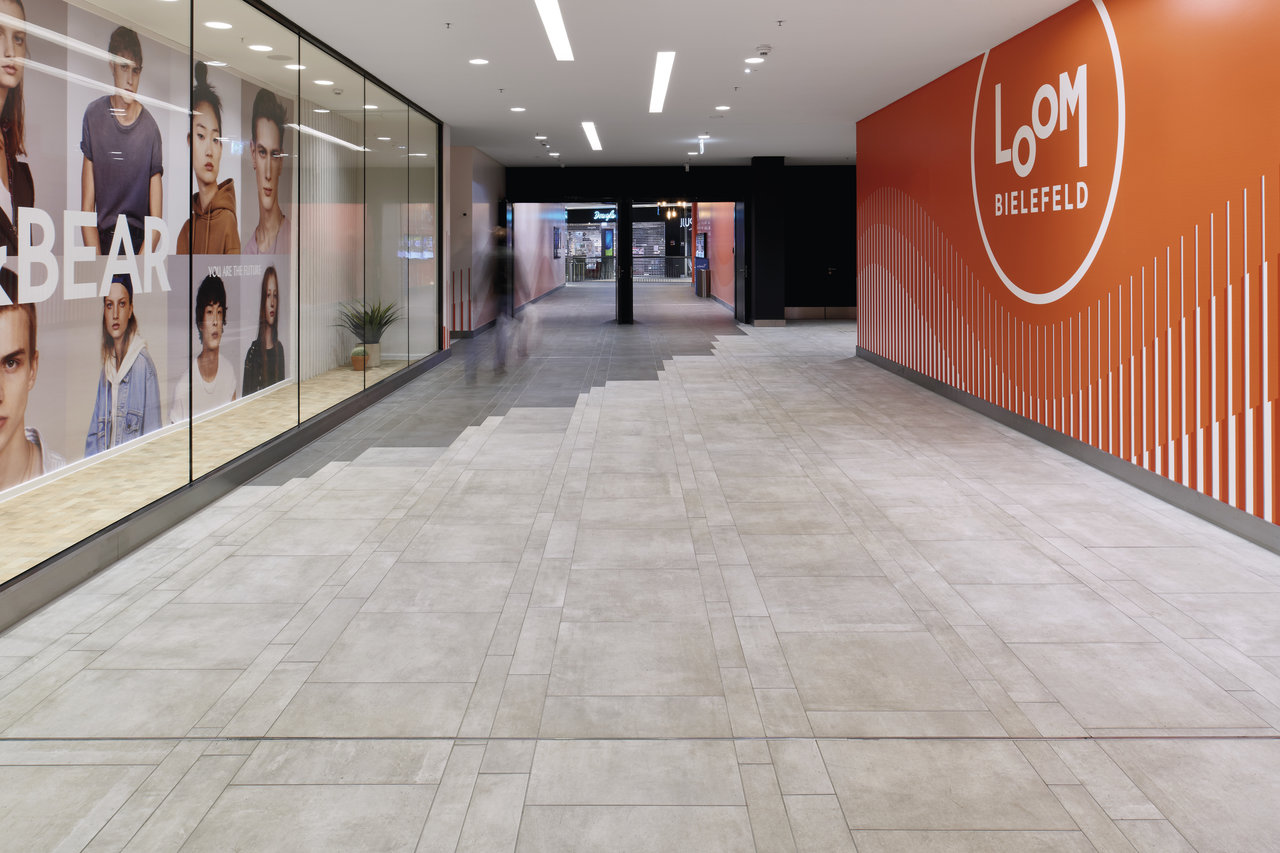 Elegant light grey large-format tiles in a shopping arcade.