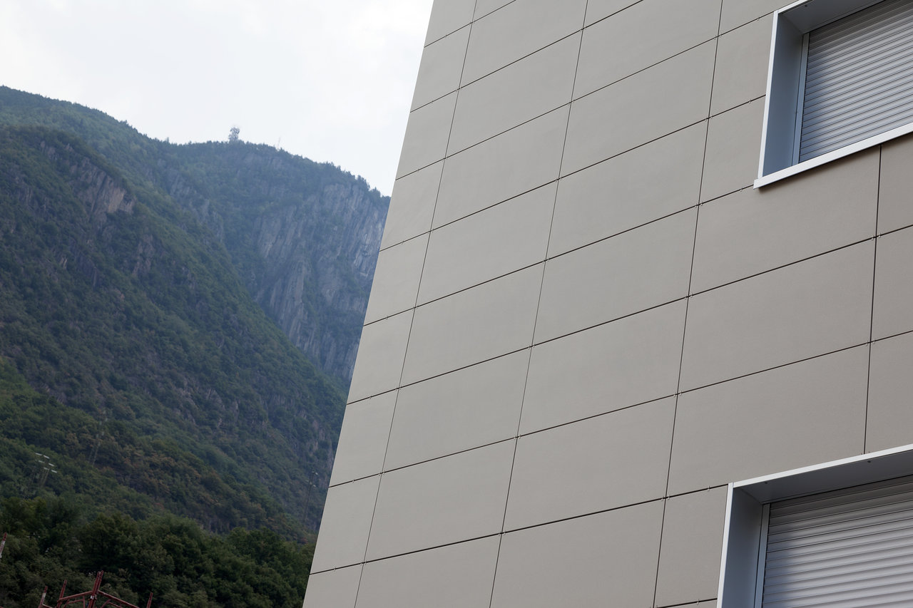 Modern grey outdoor facade tiles on a building with a mountain backdrop.
