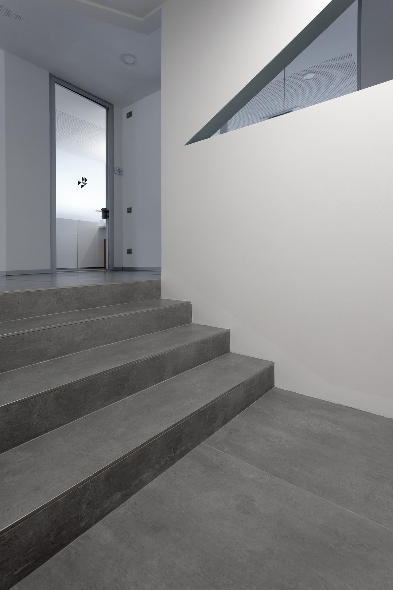 Premium dark grey tiles on stairs and floor in a modern entryway.