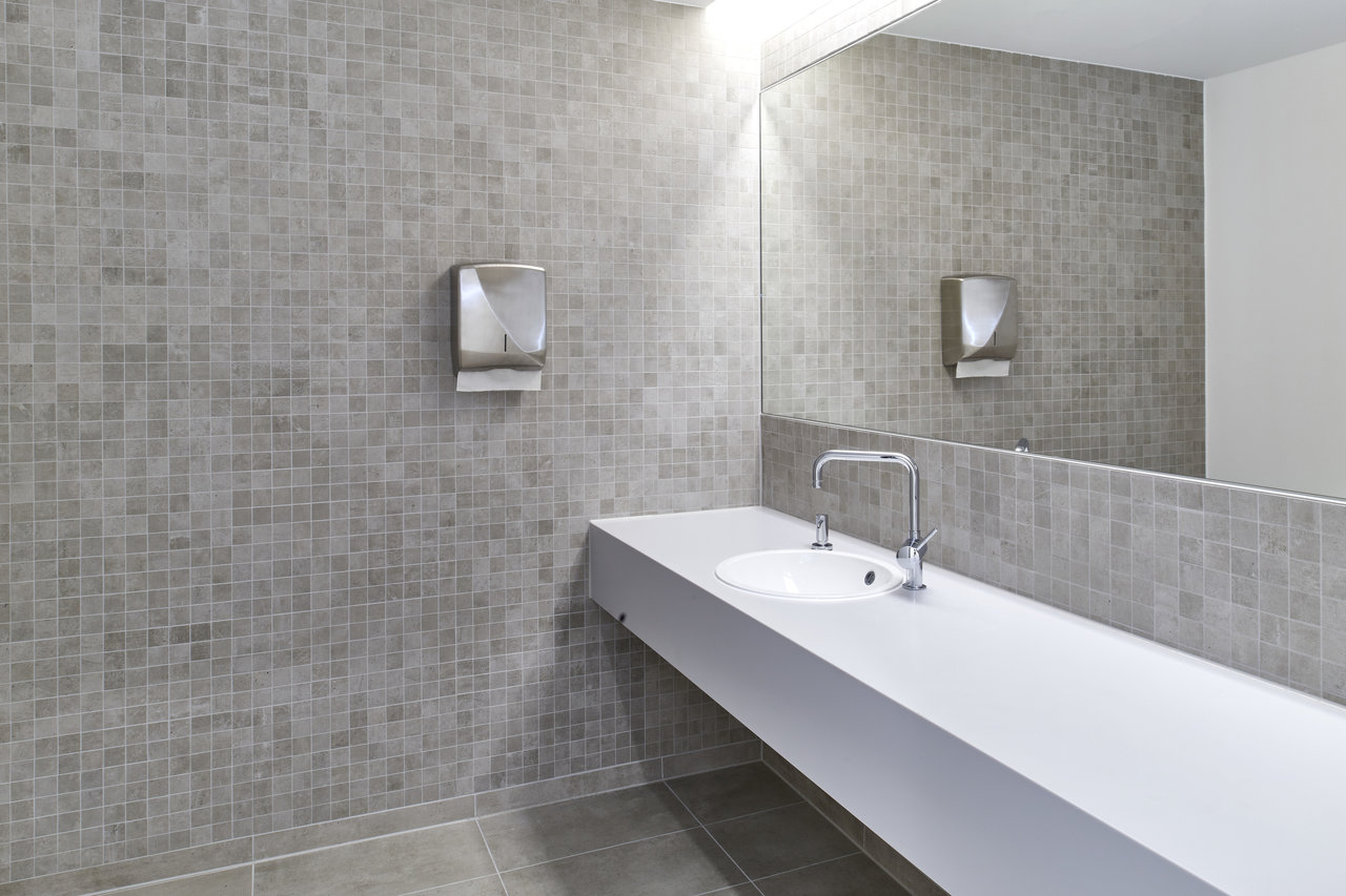 Modern bathroom with grey mosaic tiles on wall and floor, floating vanity and mirror.