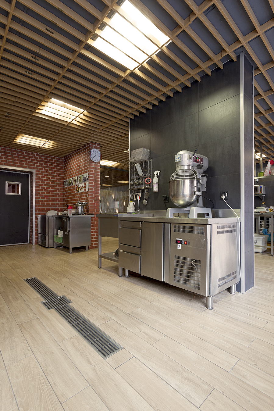 Porcelain tiles in light wood look with drainage channel in a professional kitchen.