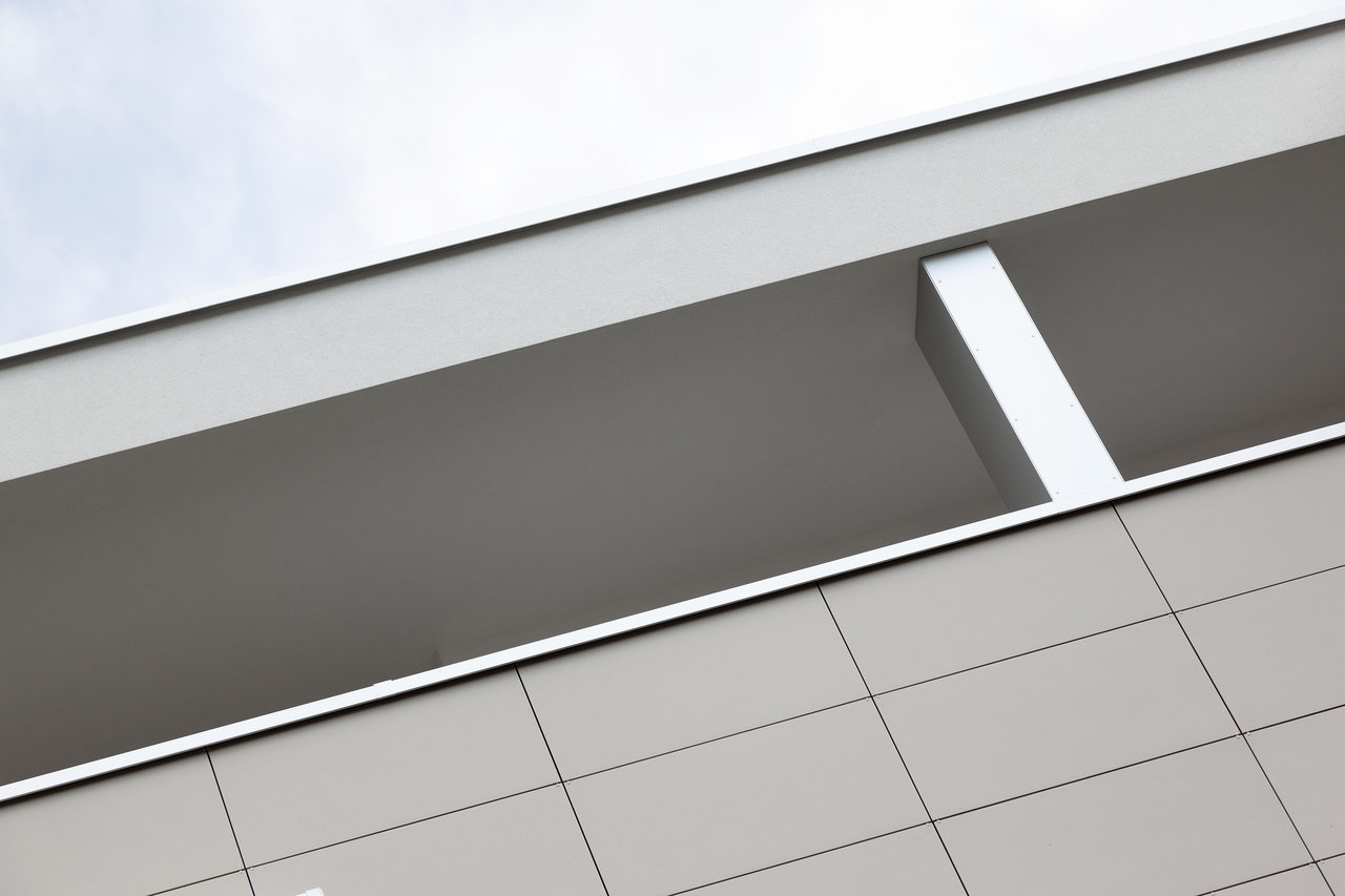 Modern building facade with light grey tiles and dark recess.