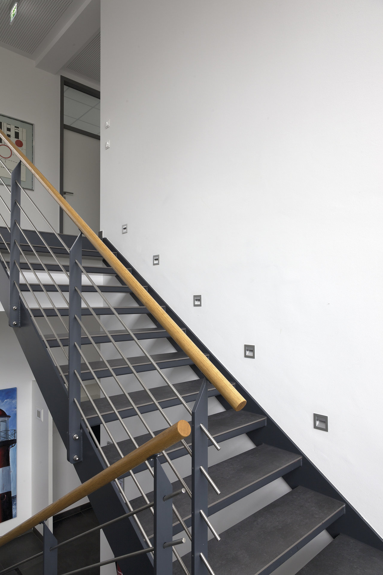 Elegant indoor staircase with dark Porcelaingres tile steps and modern railing.