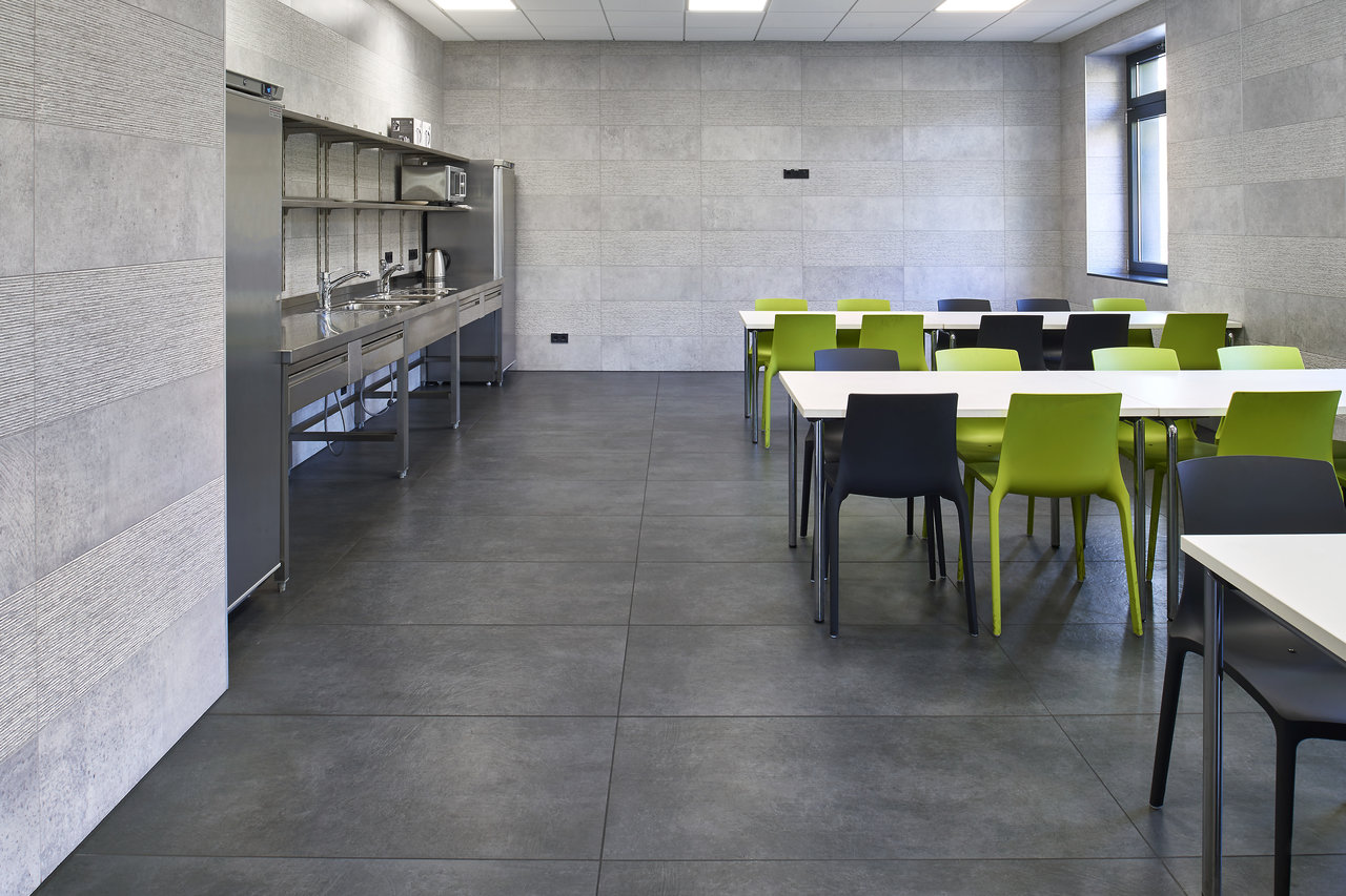 Large-format concrete-effect tiles for floors and walls of a modern canteen.