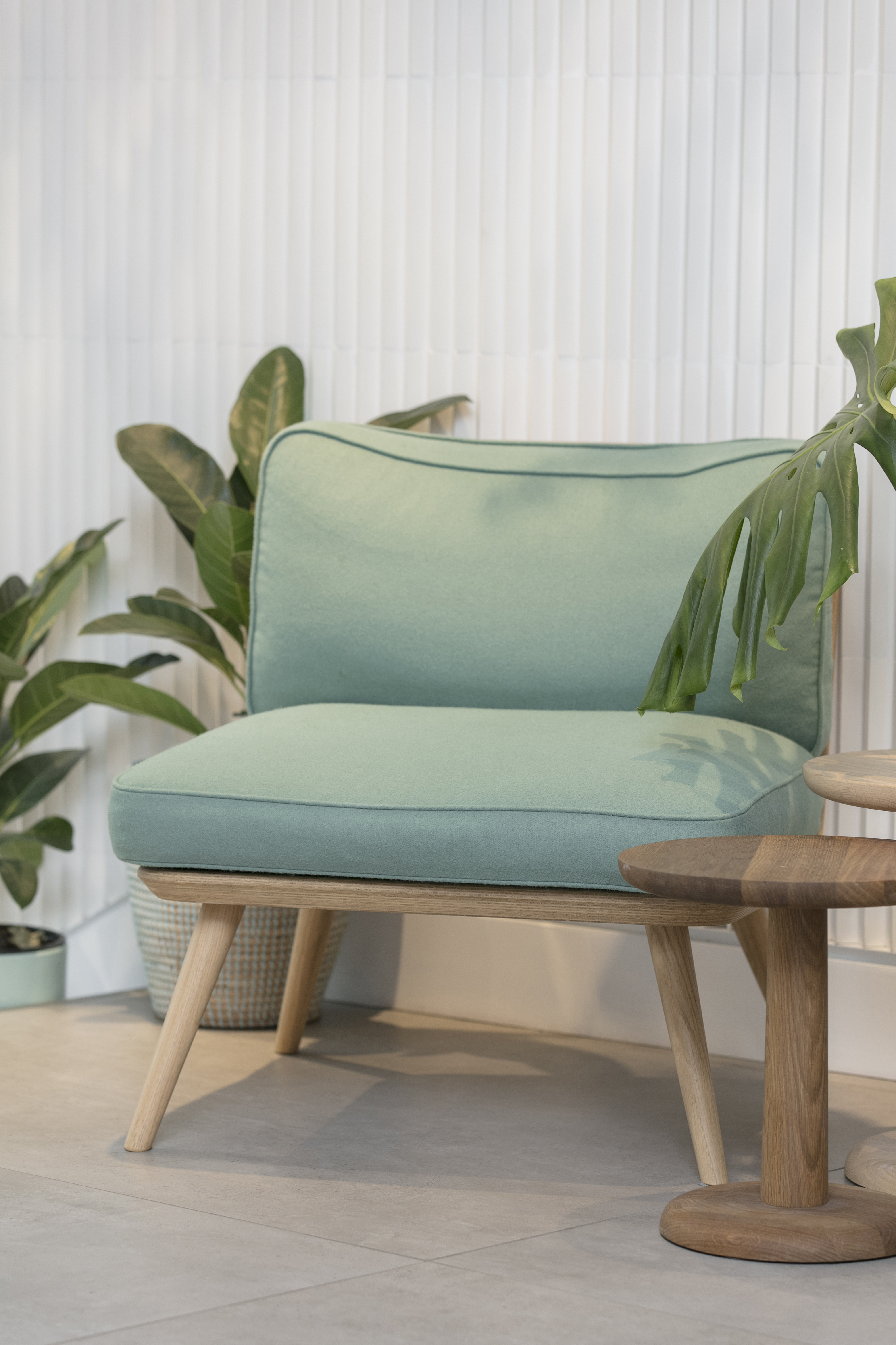 Light floor tiles and white, vertically grooved wall tiles in a modern room with a green armchair.