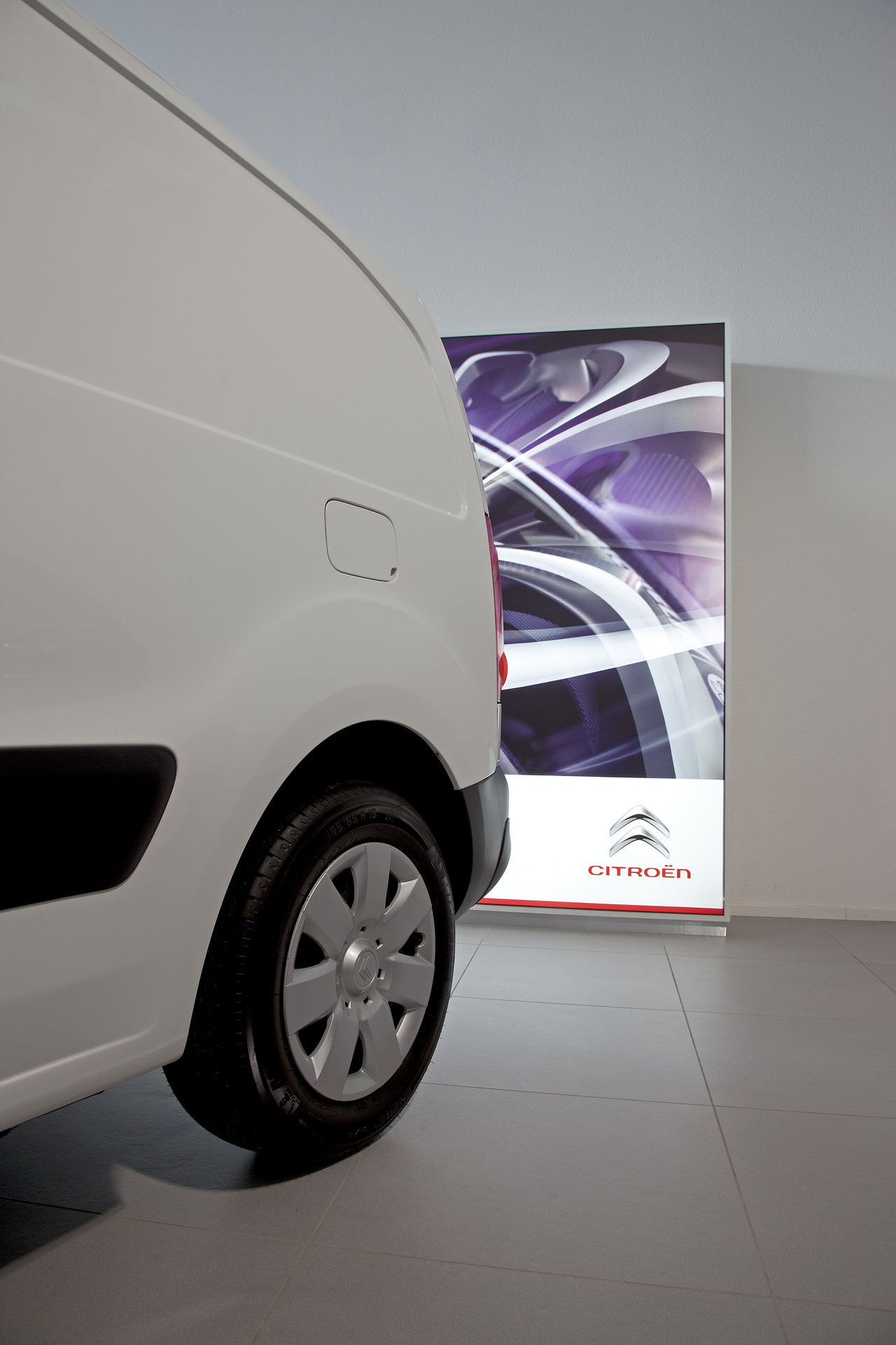 White delivery van on large-format, light-grey floor tiles.