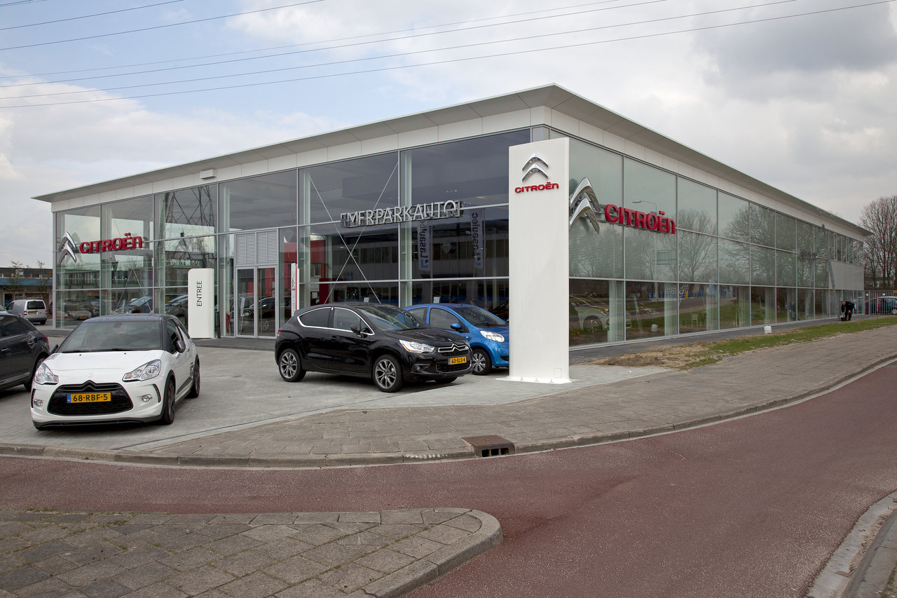 A modern Citroën car dealership with a glass facade and several parked cars.