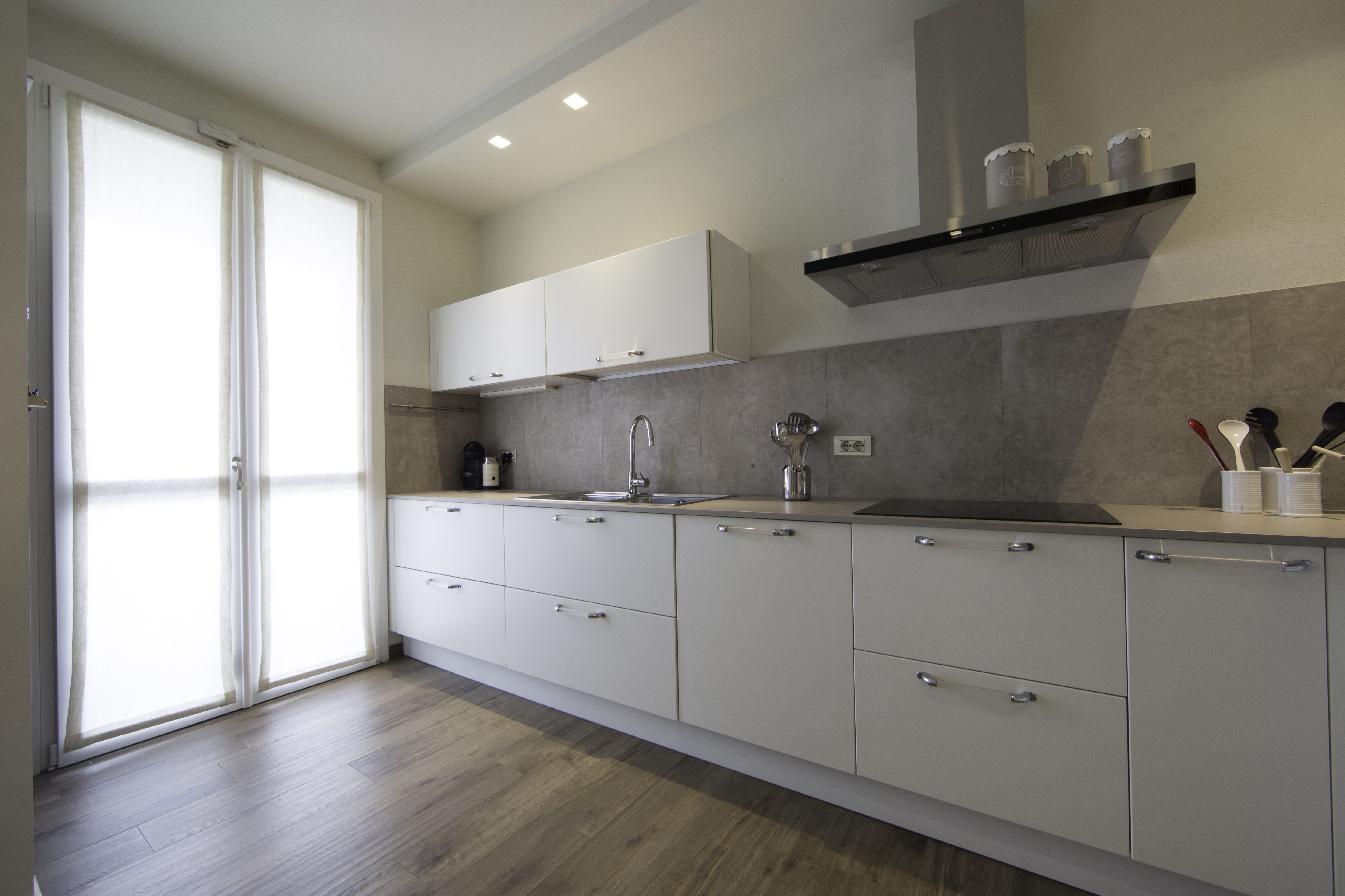 Modern kitchen with grey tile splashback and wood-look floor tiles.