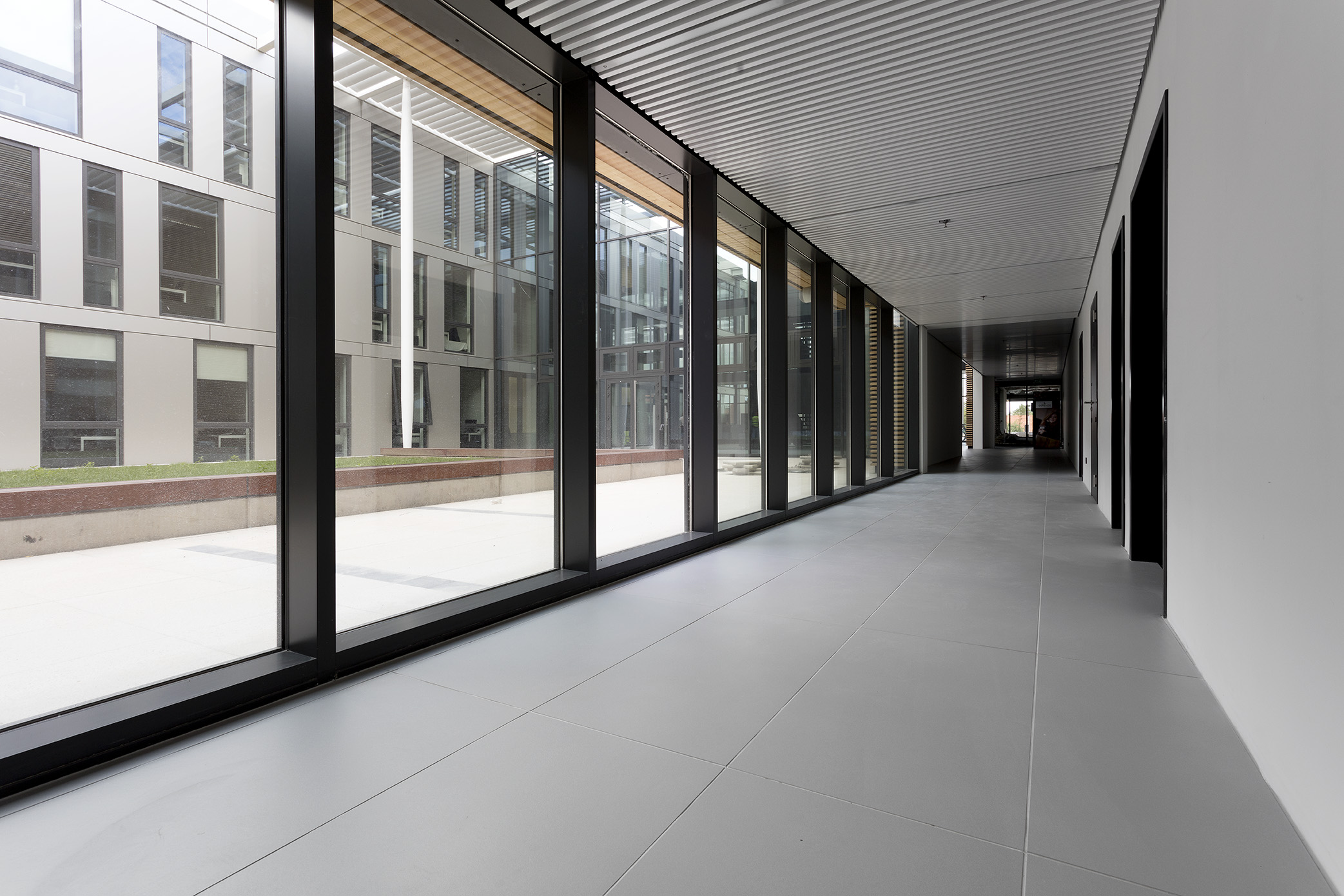 Light grey, large-format tiles in a bright, modern hallway.