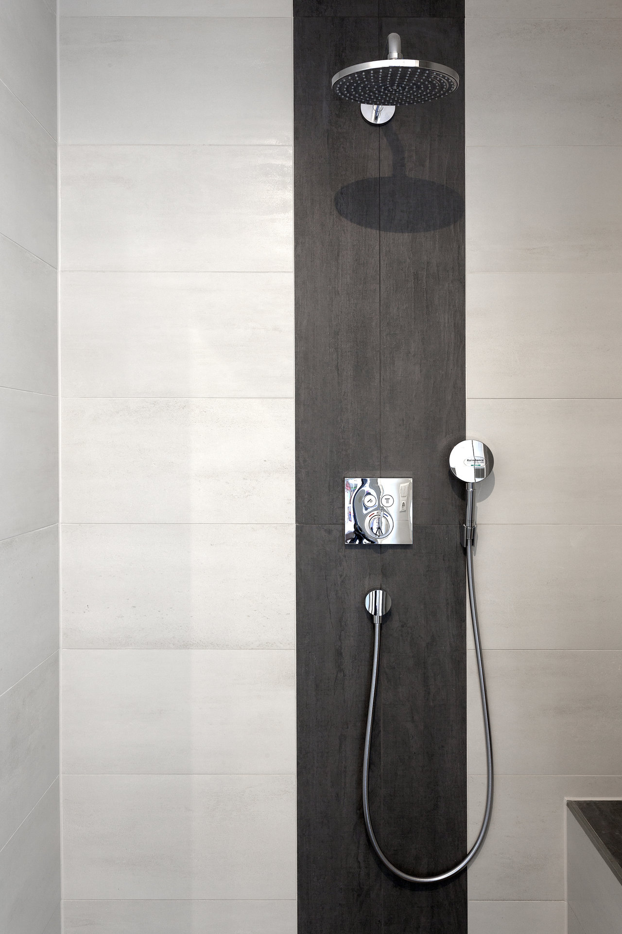 Modern shower wall with light and dark concrete-look tiles.