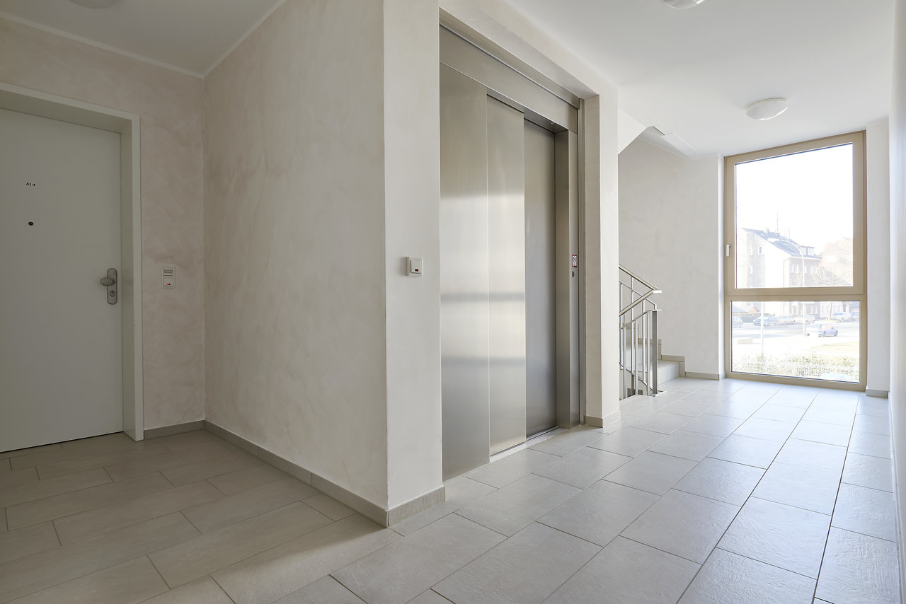 Bright, modern floor tiles in building entrance with lift.