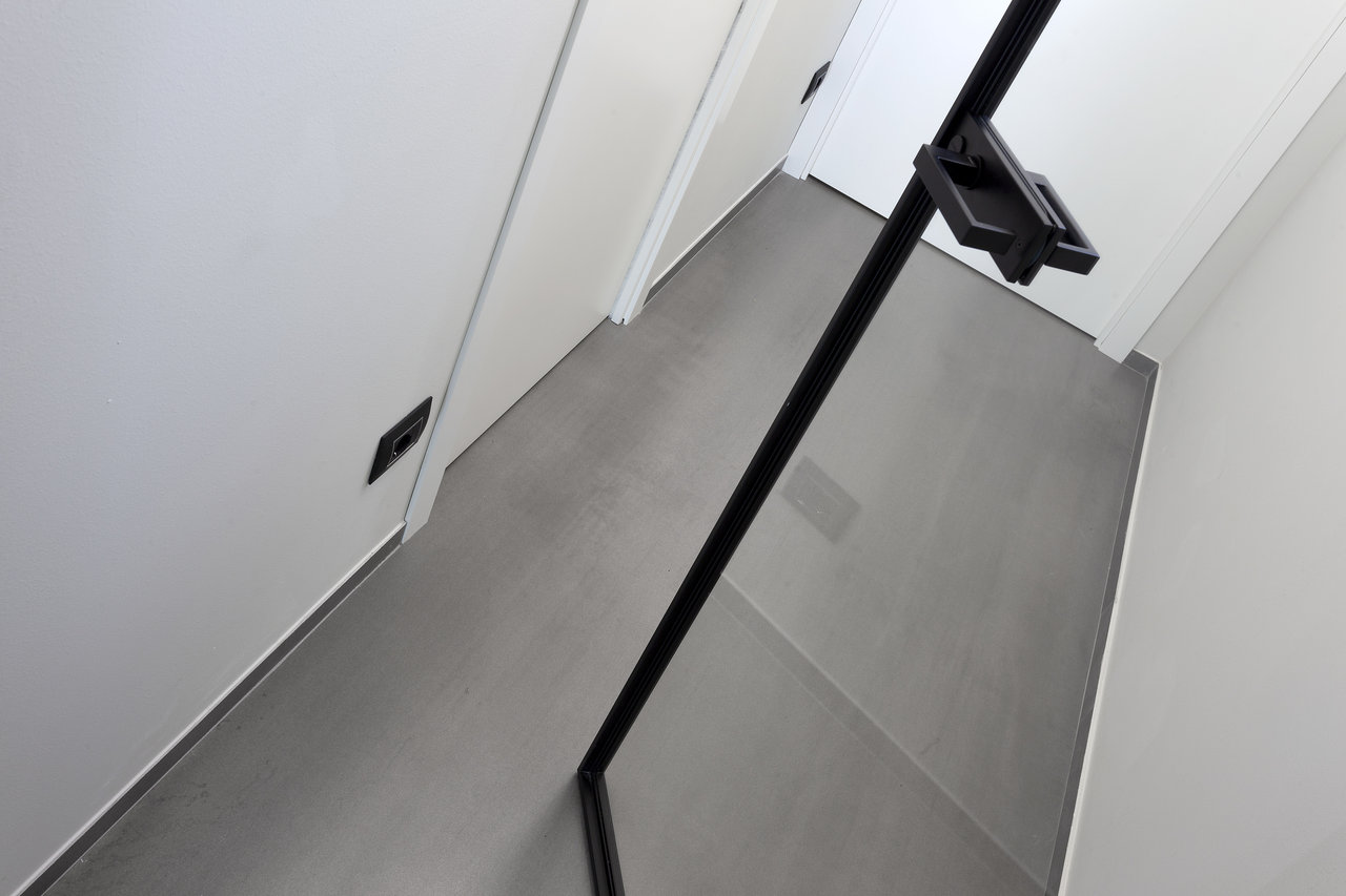 High-quality light grey concrete-effect floor tiles in a modern hallway.