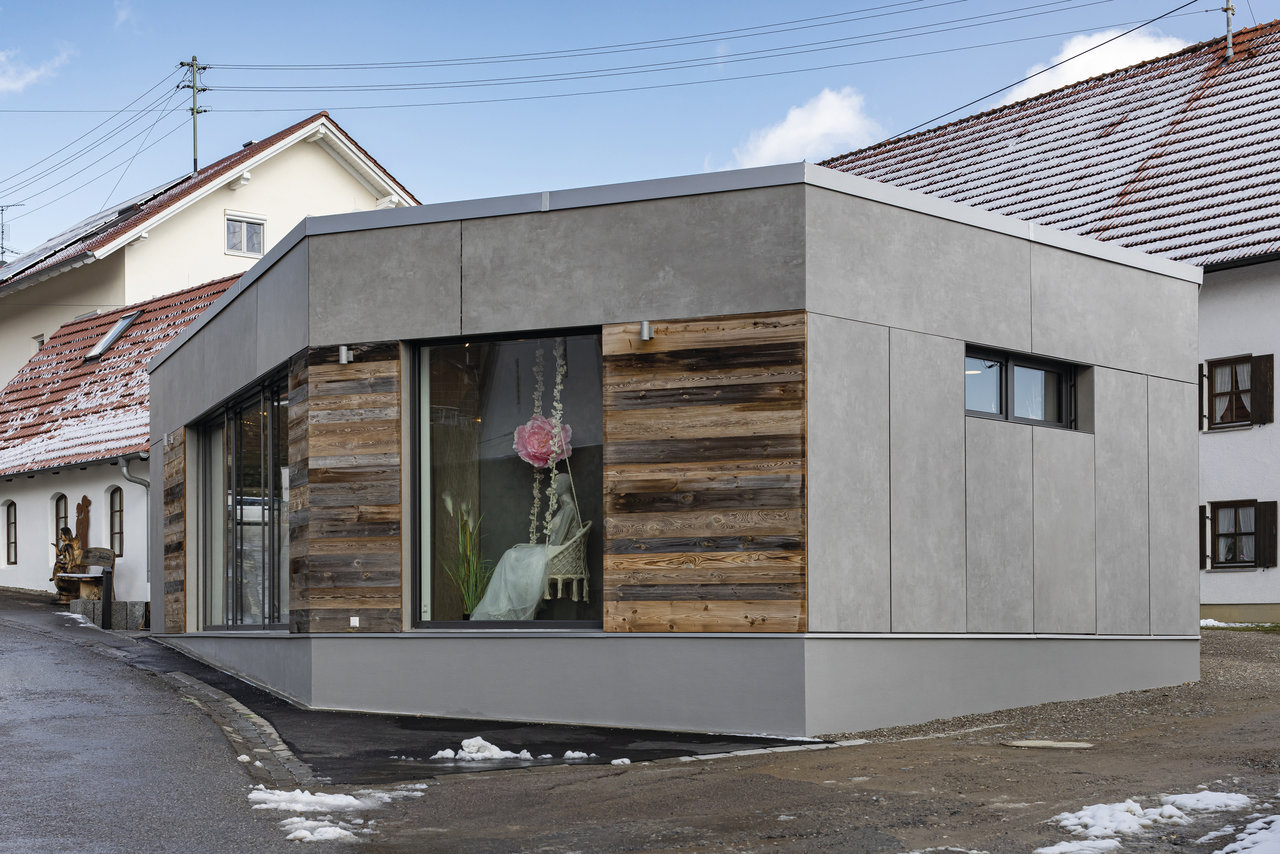 Modern facade with grey concrete-effect panels and wood cladding.