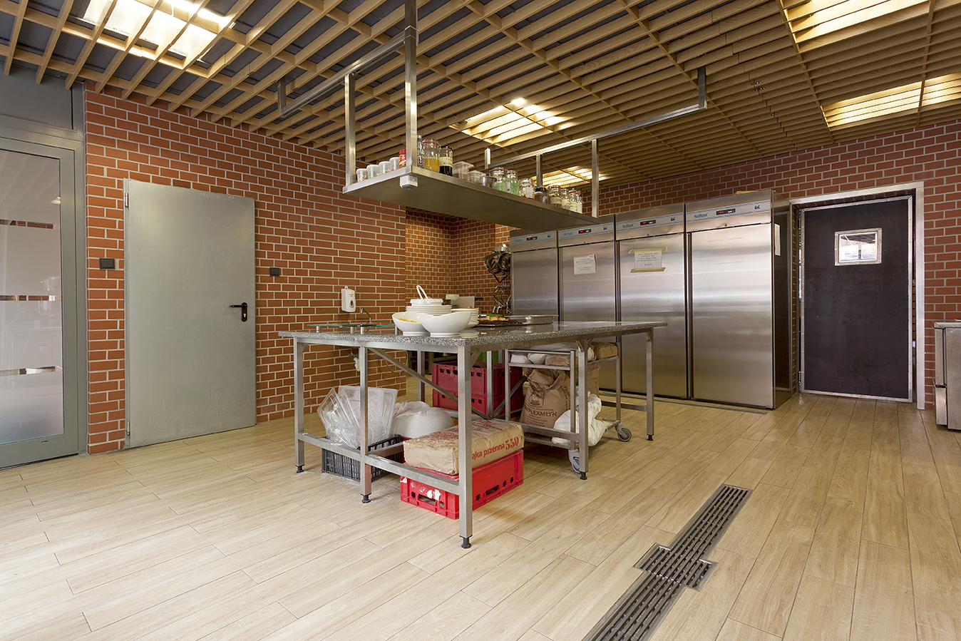 High-quality light floor tiles in a modern commercial kitchen with brick walls.