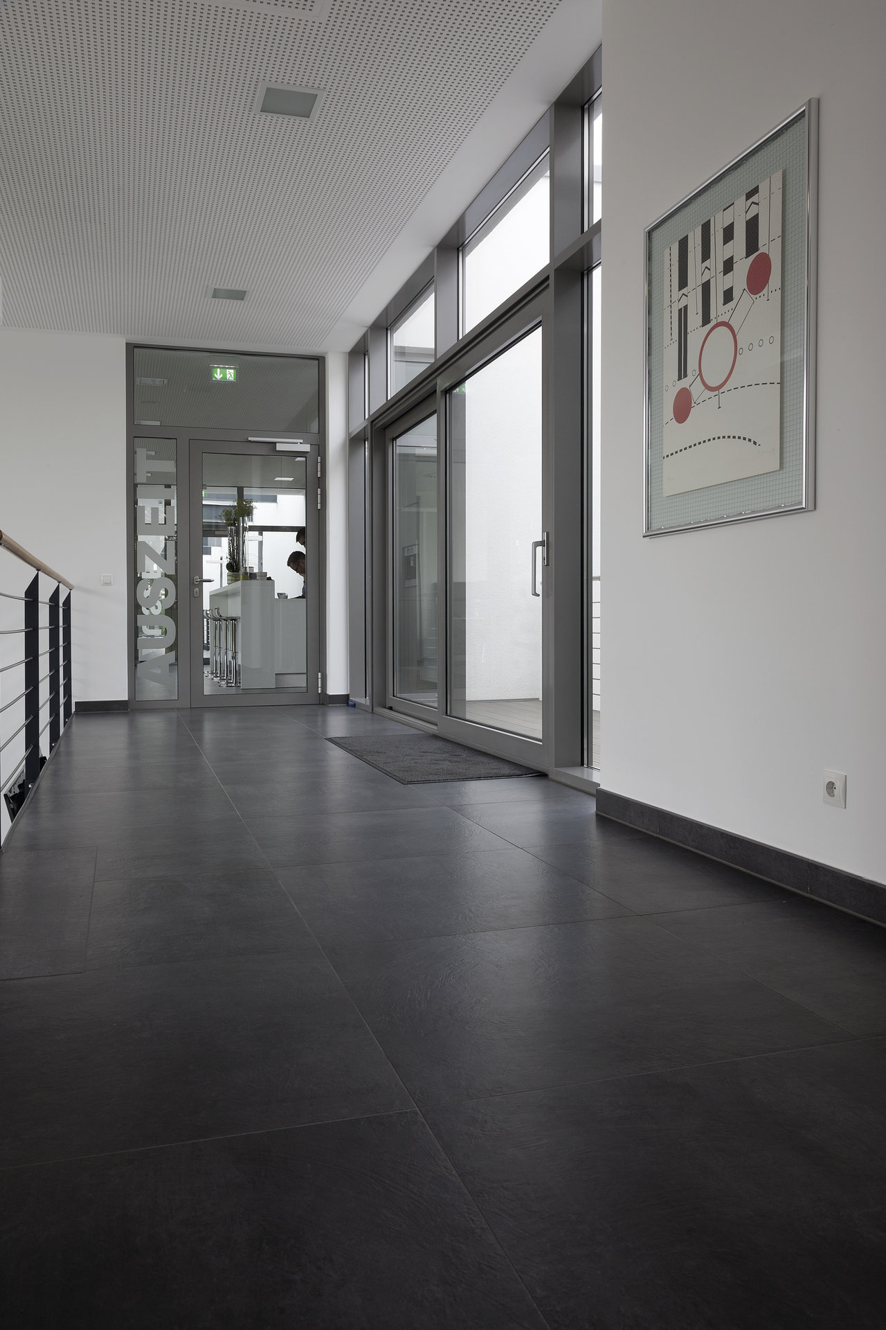 High-quality, large-format anthracite tiles in a modern hallway with natural light.