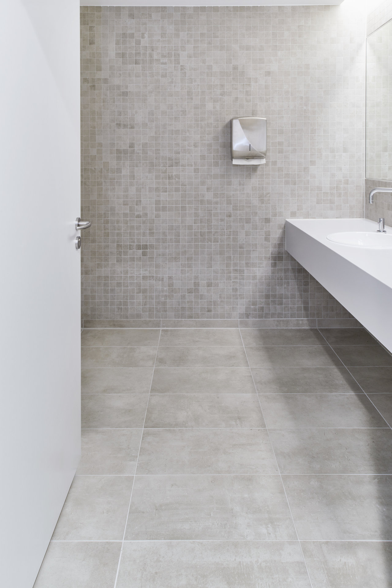 Grey floor tiles and mosaic wall tiles in a modern bathroom.