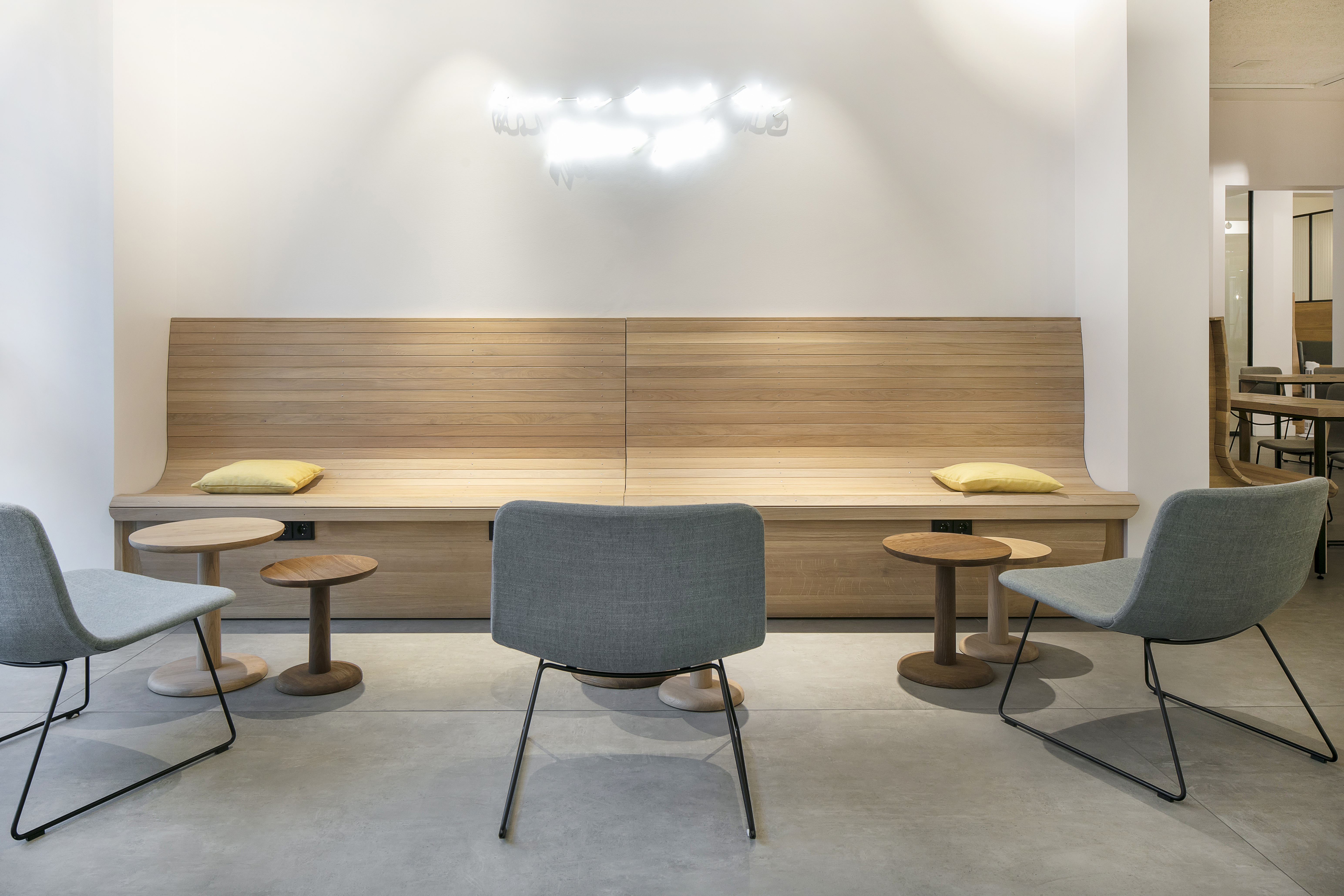 Bright interior with modern tiled floor, wooden bench, and grey chairs.