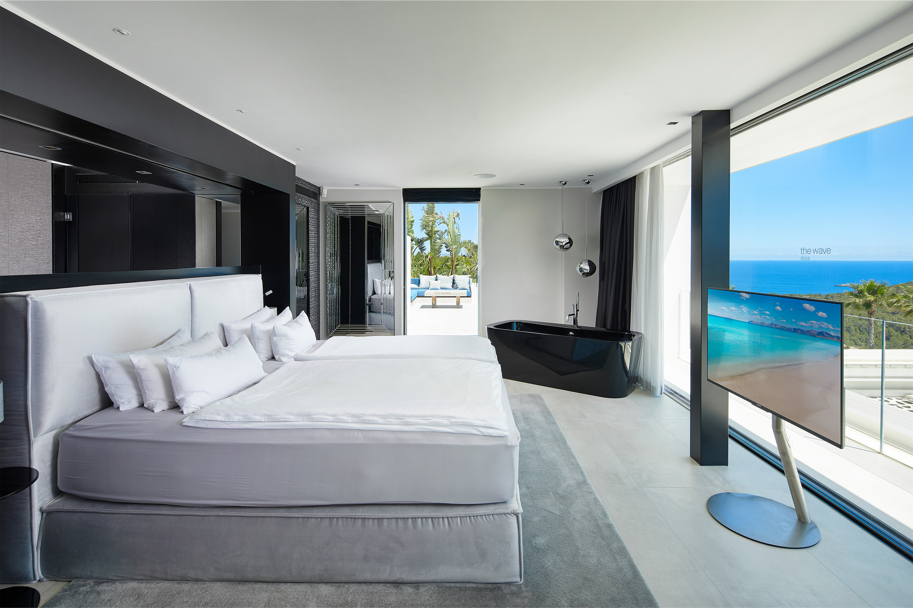 Bedroom with sea view, freestanding bathtub, and bright, modern floor tiles.