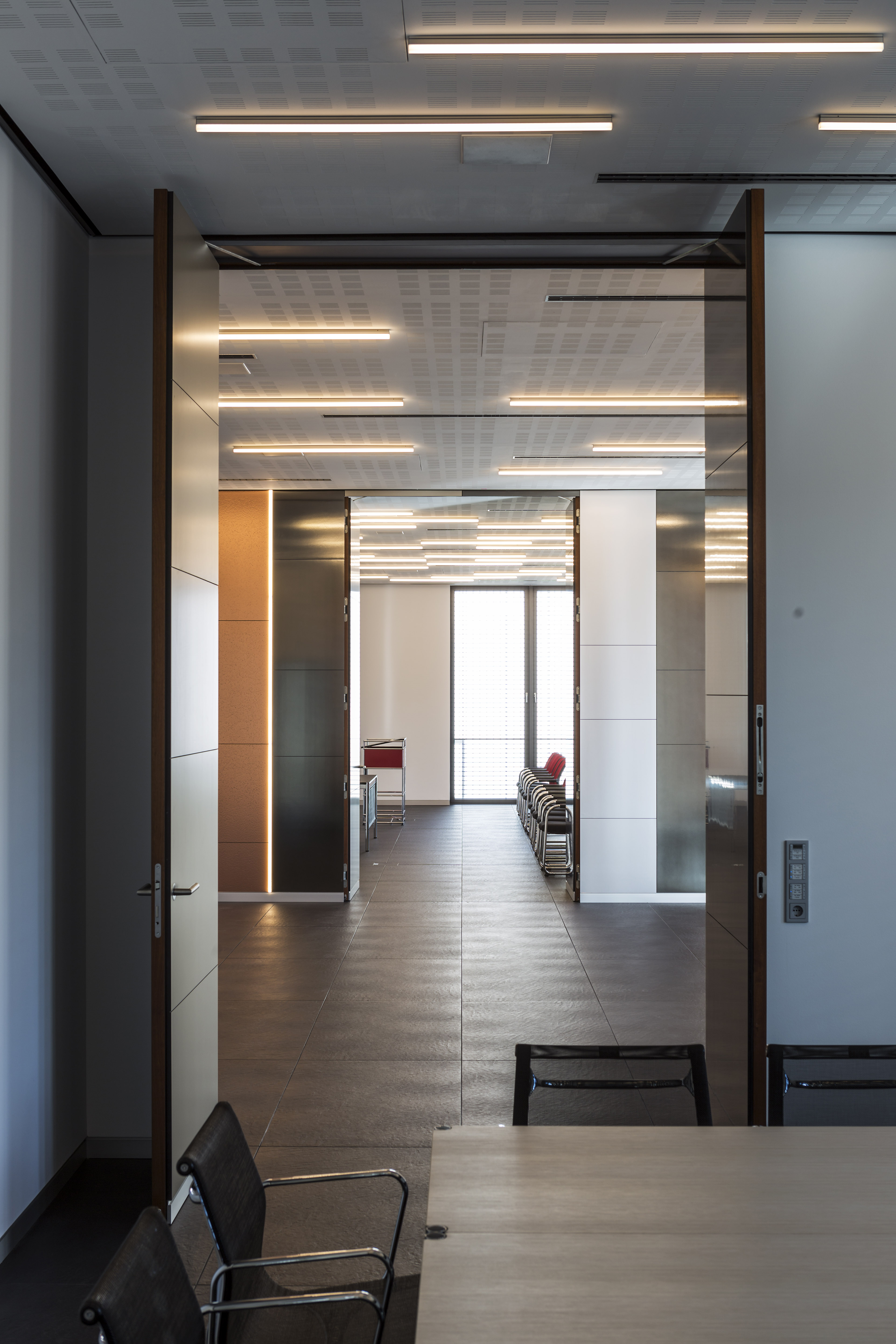 Bright, modern hallway with dark, large-format floor tiles and ceiling lights.
