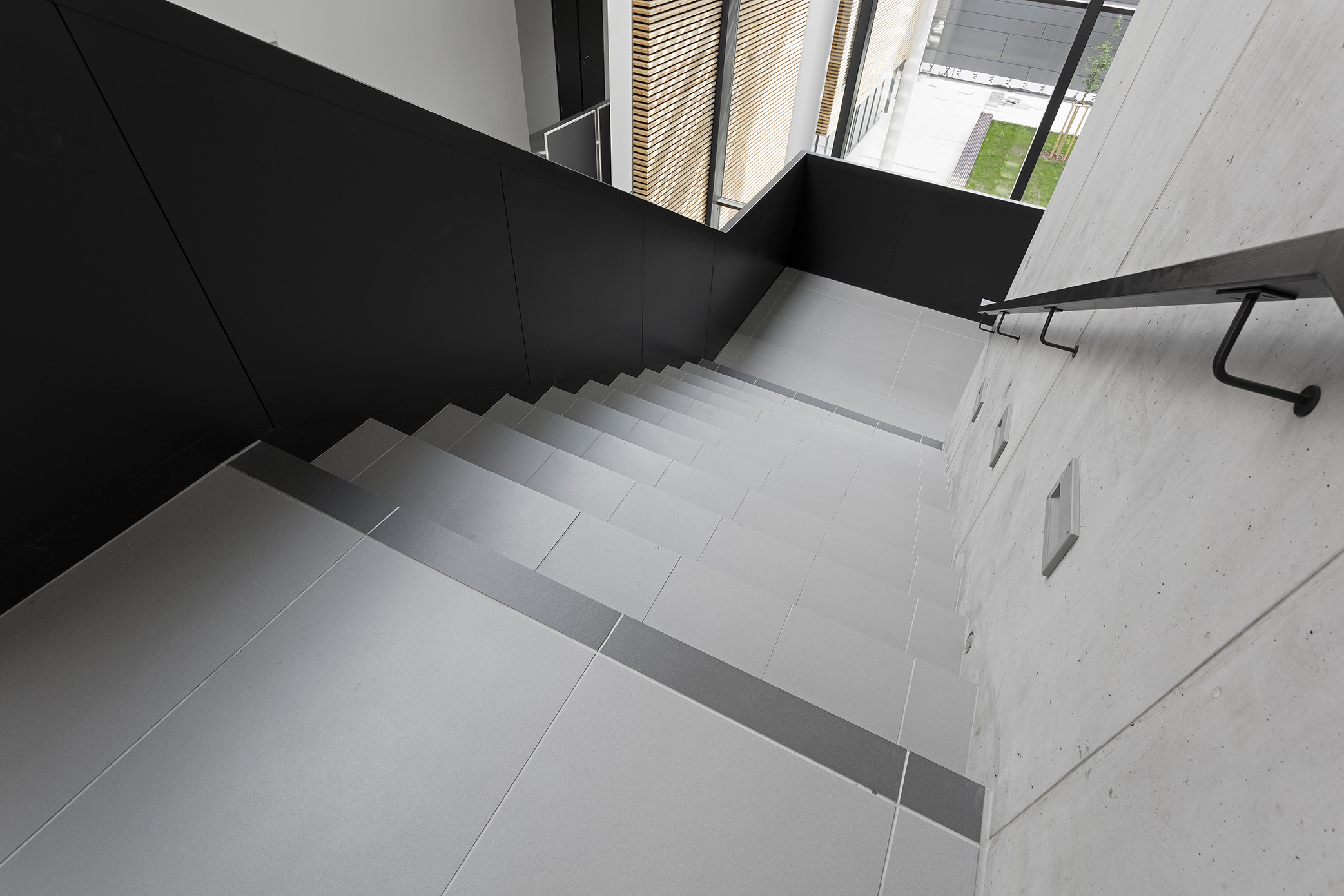 High-quality, light grey tiles on a modern staircase with a dark accent.