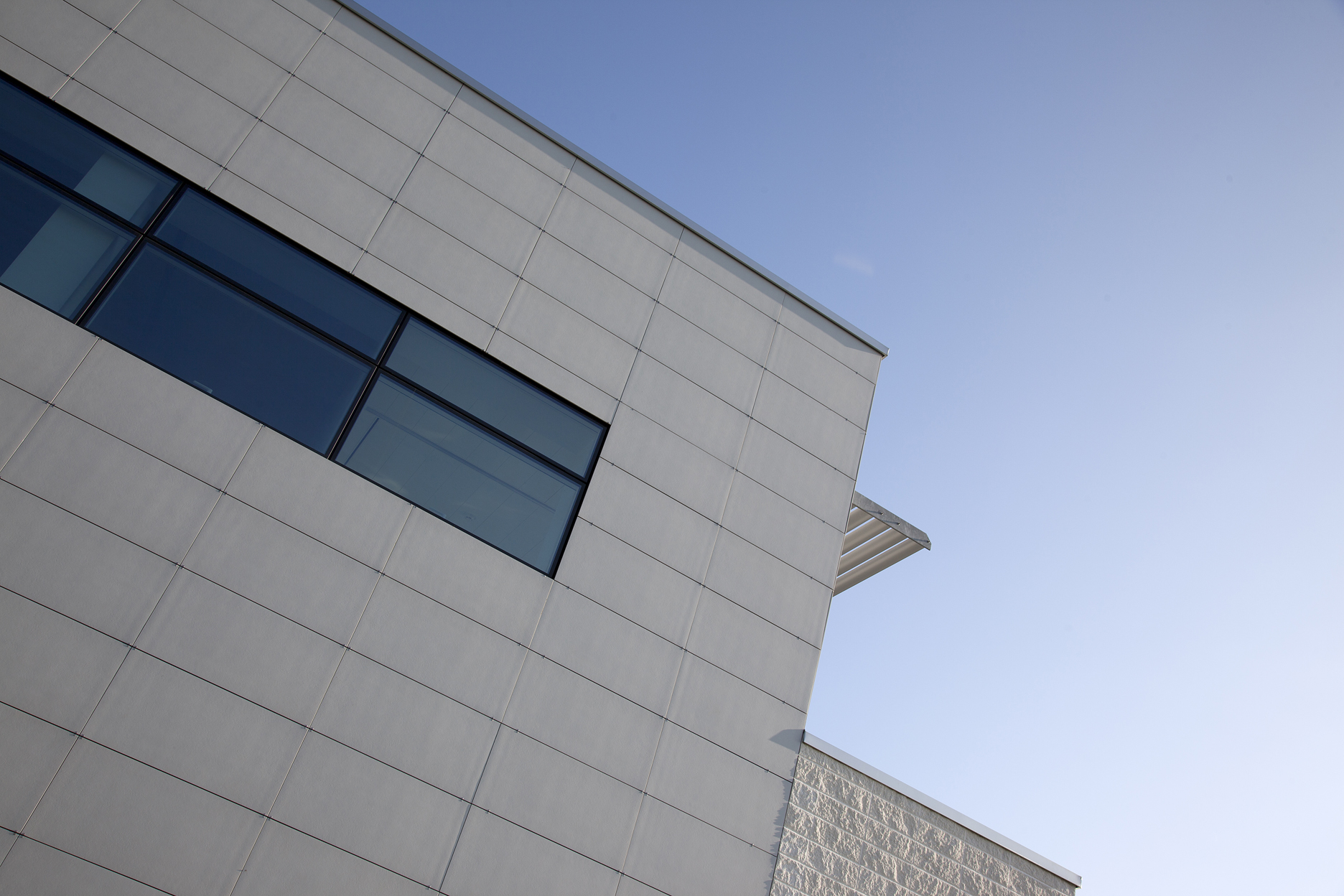 Modern facade with large-format, light-coloured tiles and windows.