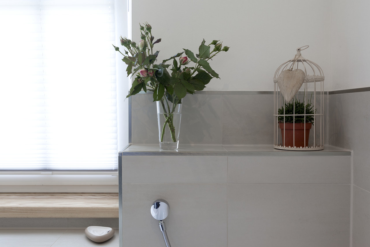 Light porcelain tiles in shower area with integrated shelf and stylish decoration.