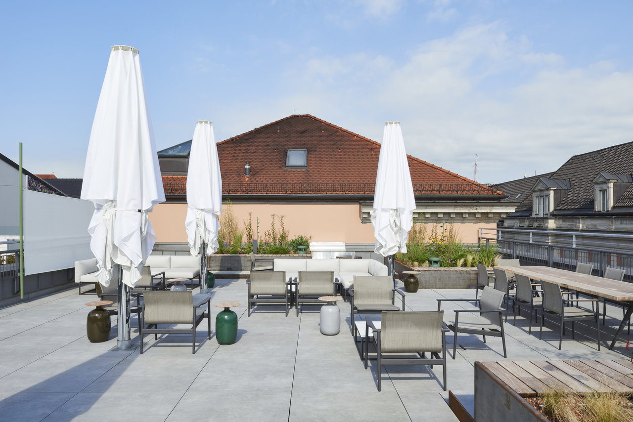 Bright outdoor tiles on a spacious roof terrace with lounge furniture and parasols.
