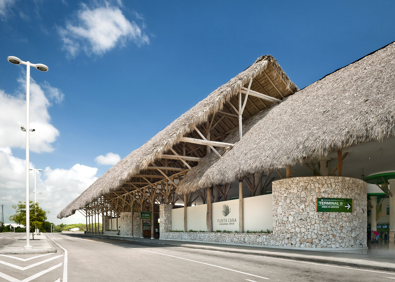 Tropical airport terminal with natural stone walls and thatched roof, ideal for outdoor tile inspiration.