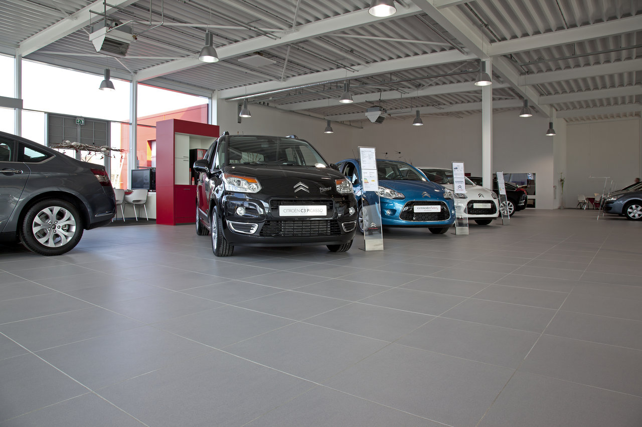 Large-format, light grey floor tiles in a modern car dealership.