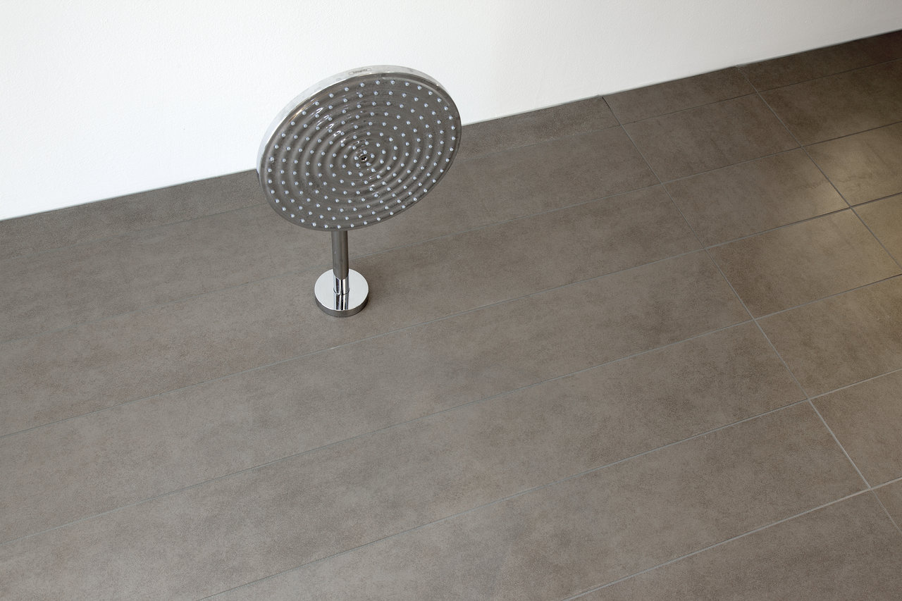 Elegant, dark grey porcelain stoneware tiles in bathroom with modern shower head.