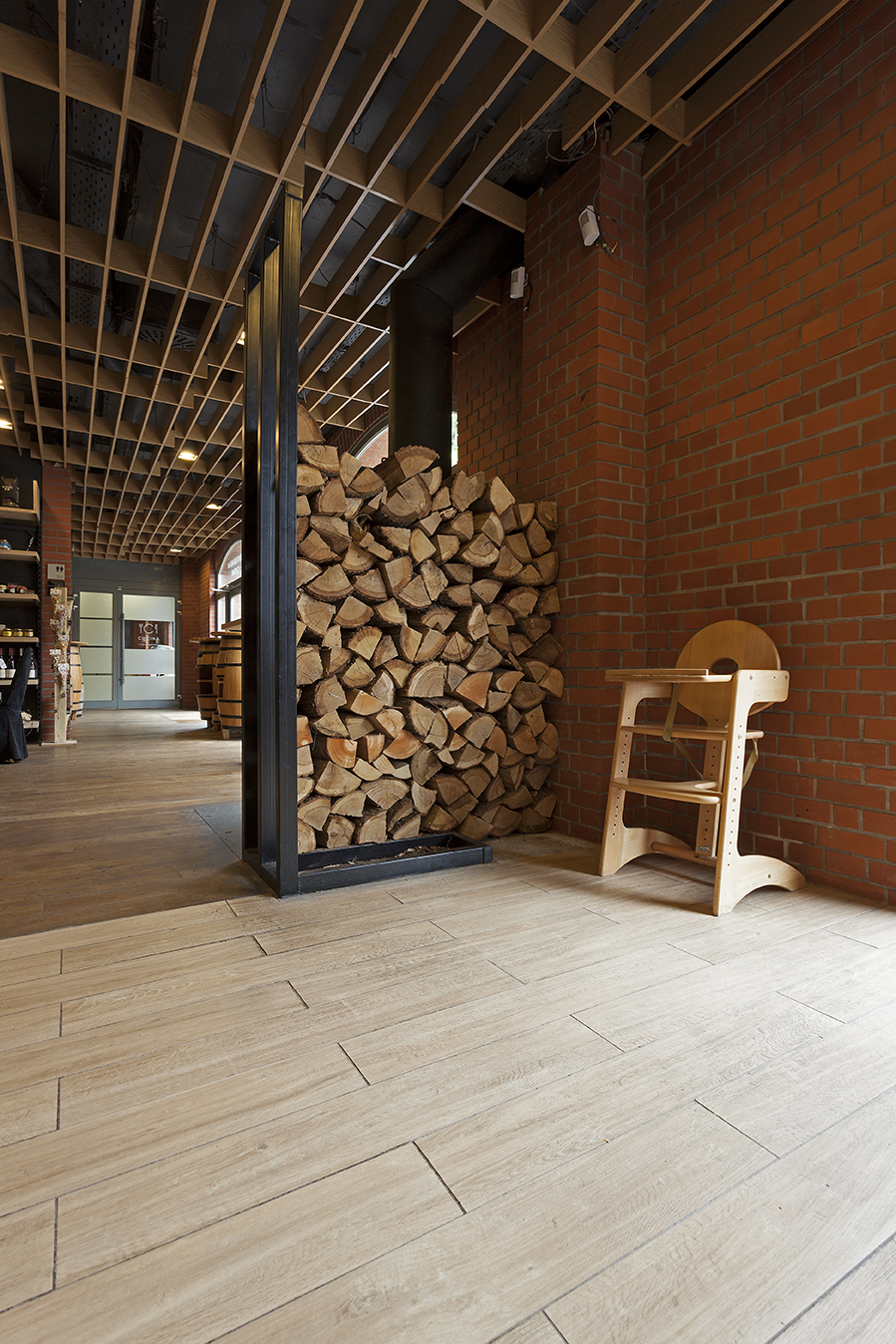 Light wood-look tiles in a room with a brick wall and firewood.