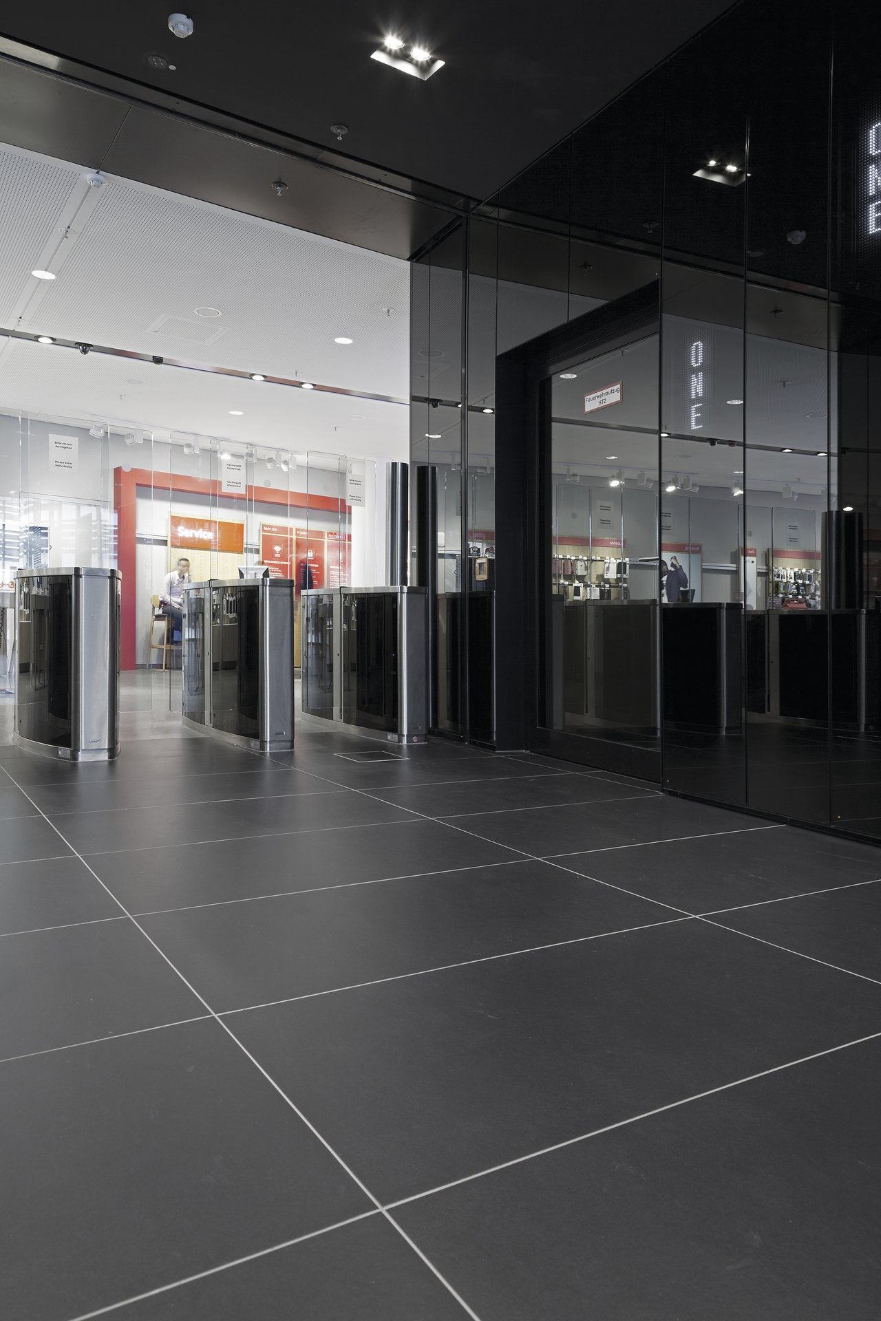 Elegant anthracite large-format tiles with light grout in a modern business setting.