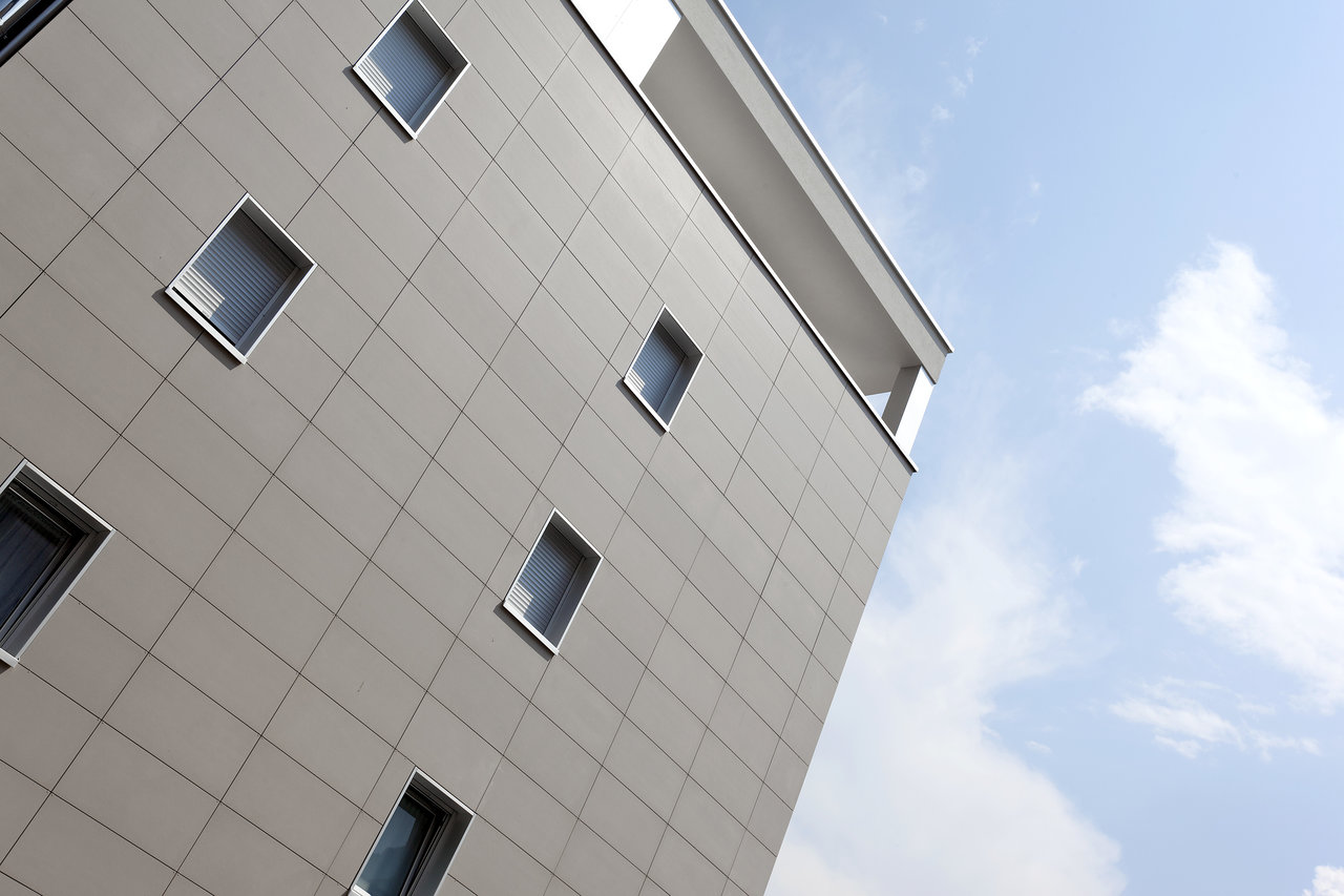 Modern building facade with large-format grey tiles.