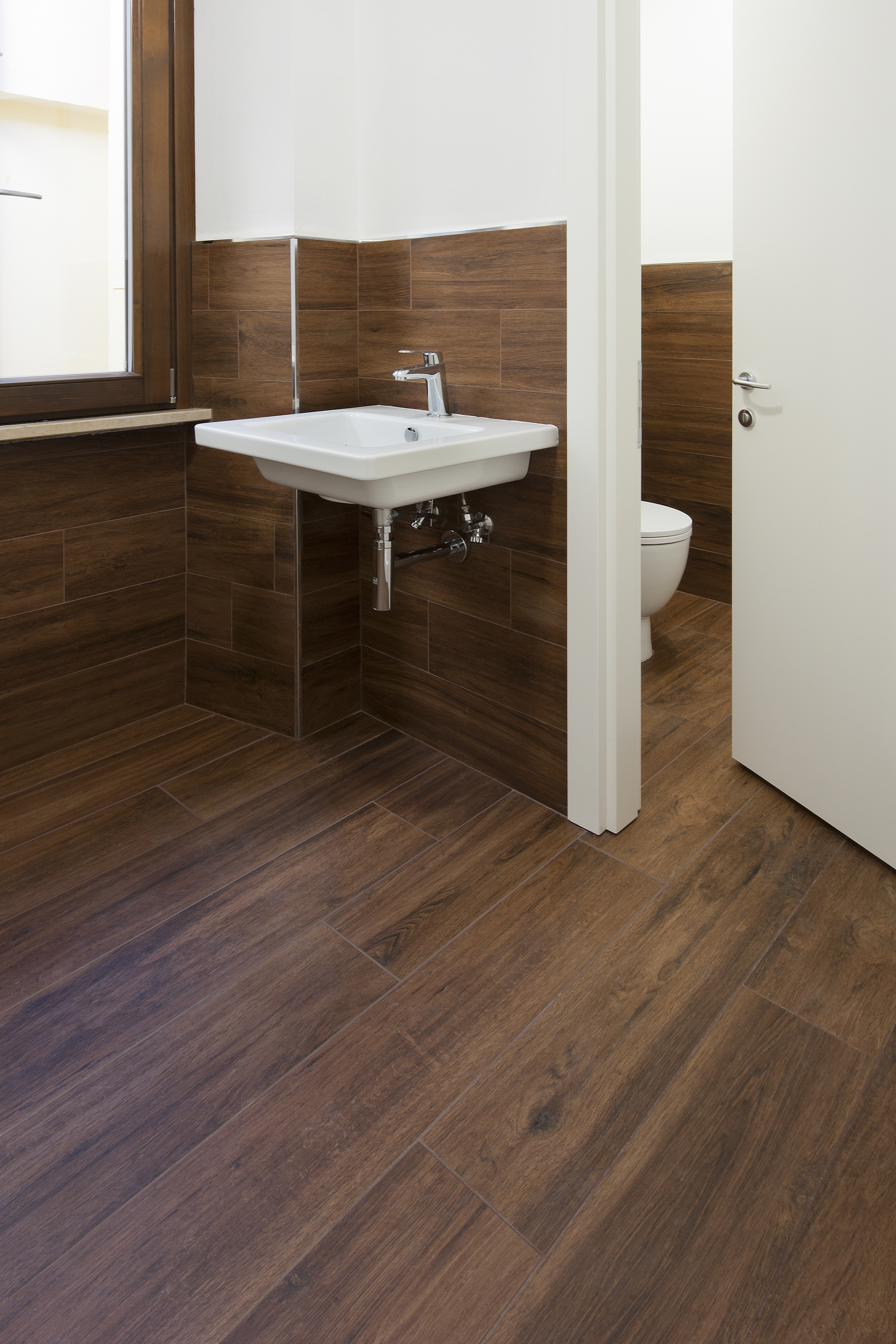 Modern bathroom with premium dark wood-effect floor and wall tiles.