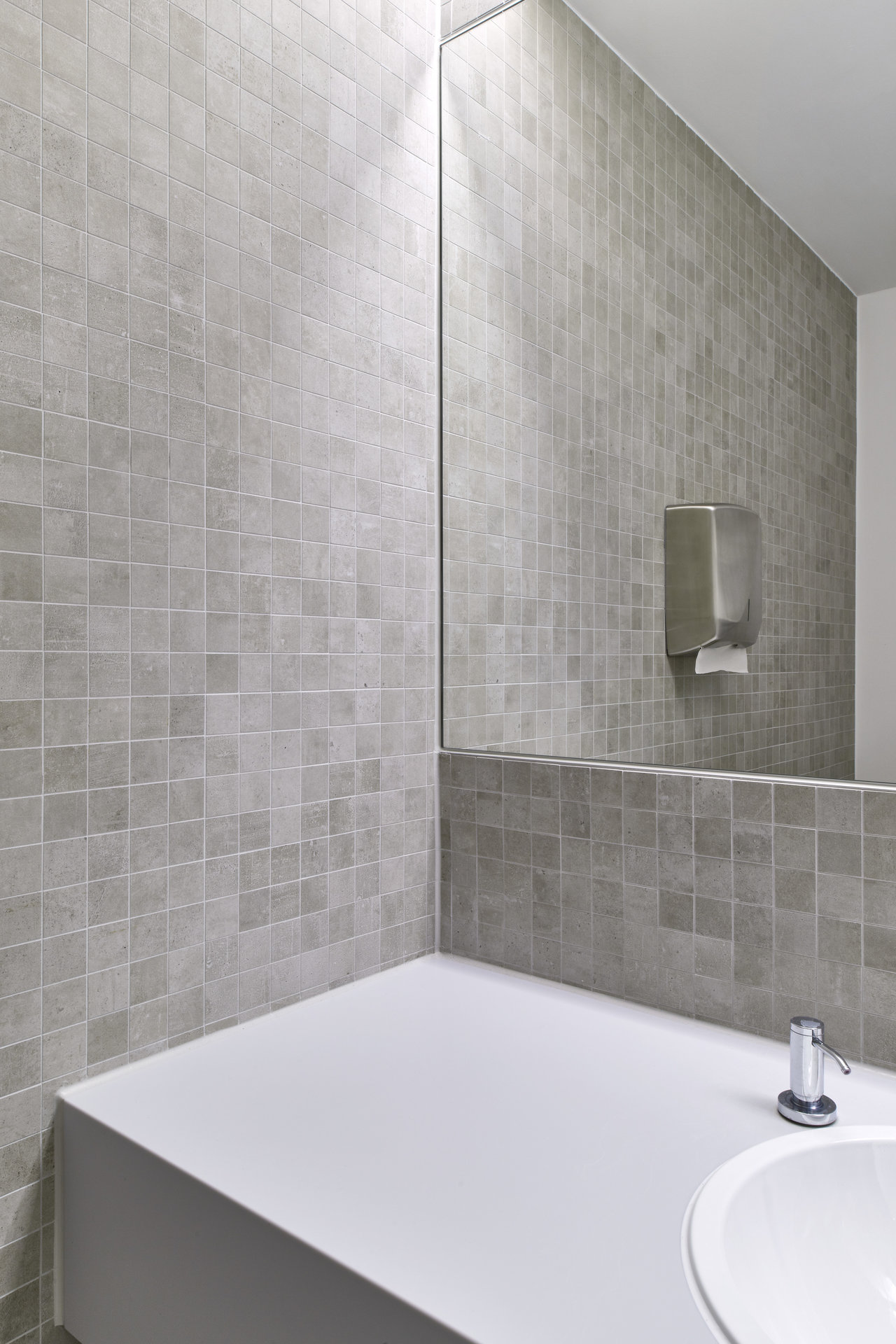Light grey mosaic wall tiles in a modern bathroom with a vanity.