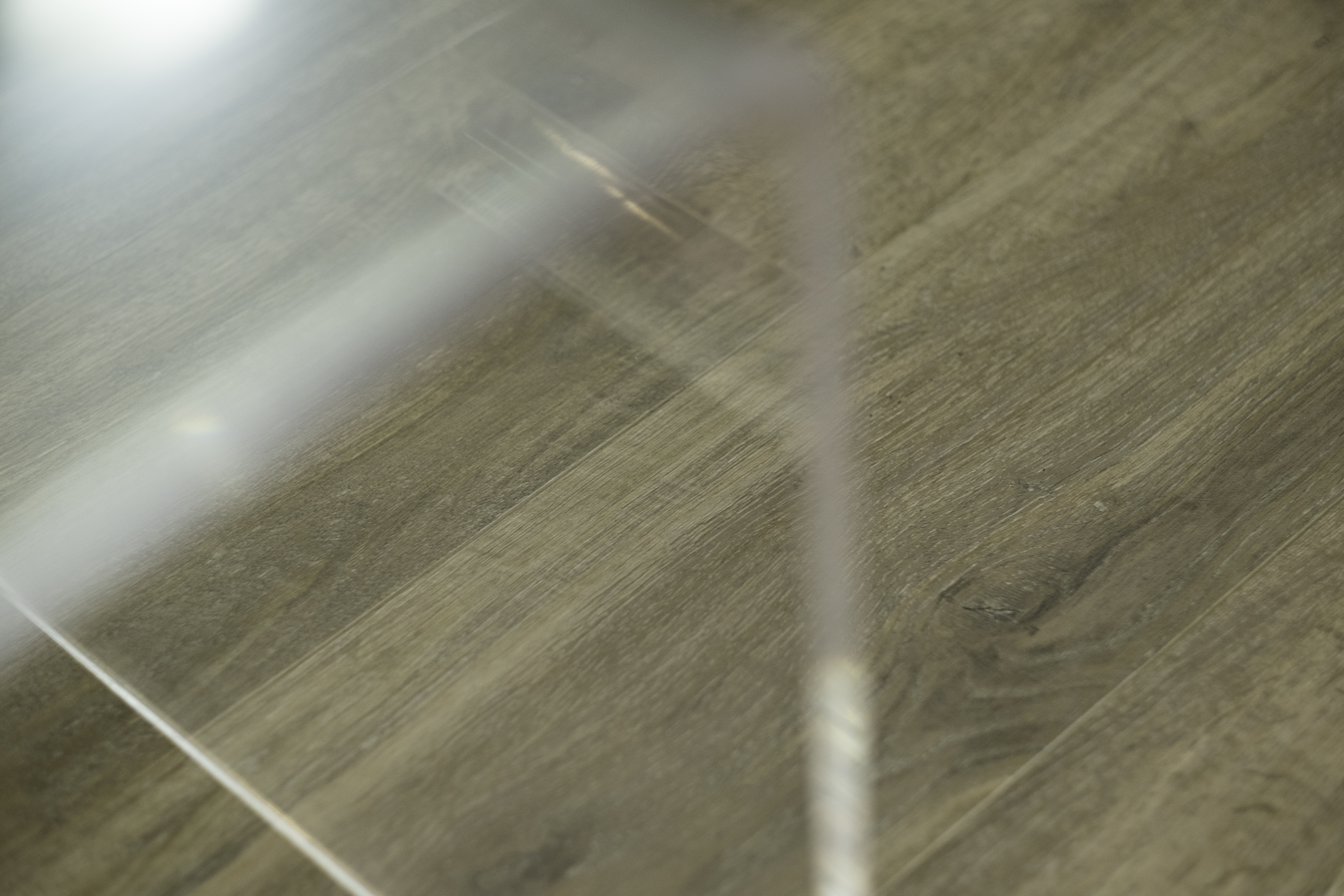 Glossy wood-effect tile with grain and light reflections.