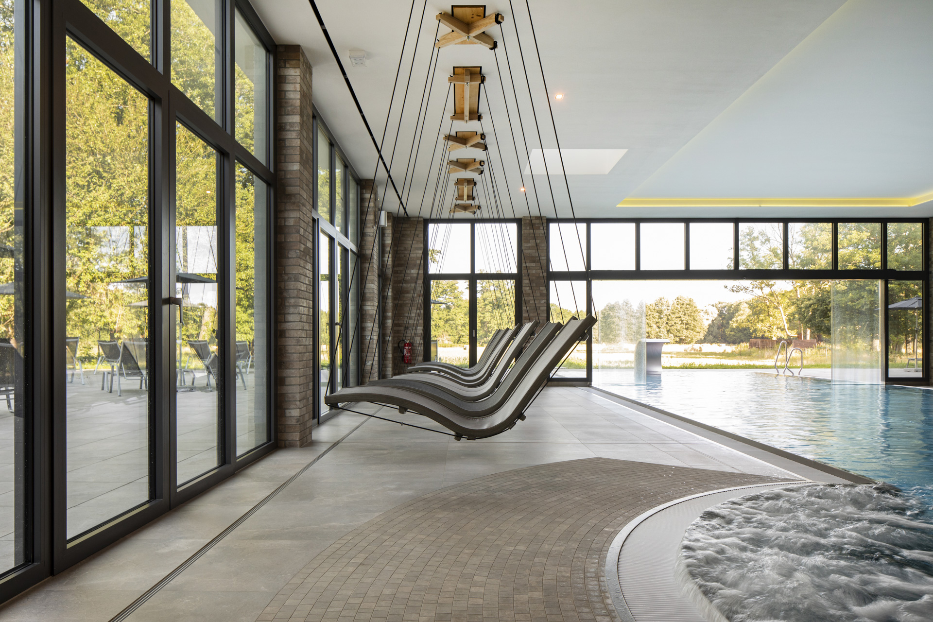 Modern wellness area with large-format tiles, pool, whirlpool, and panoramic windows.