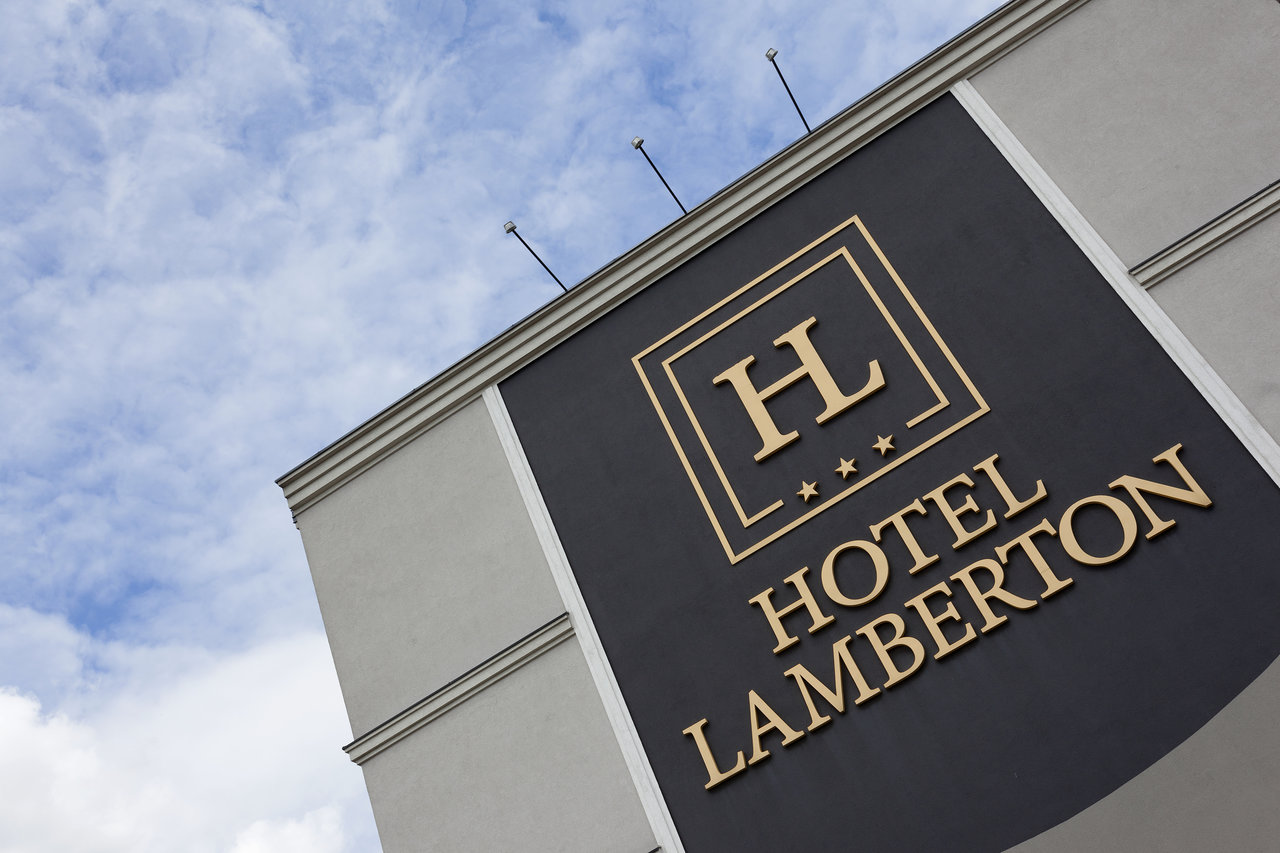 Golden Hotel Lamberton sign on a dark building facade under a blue sky.
